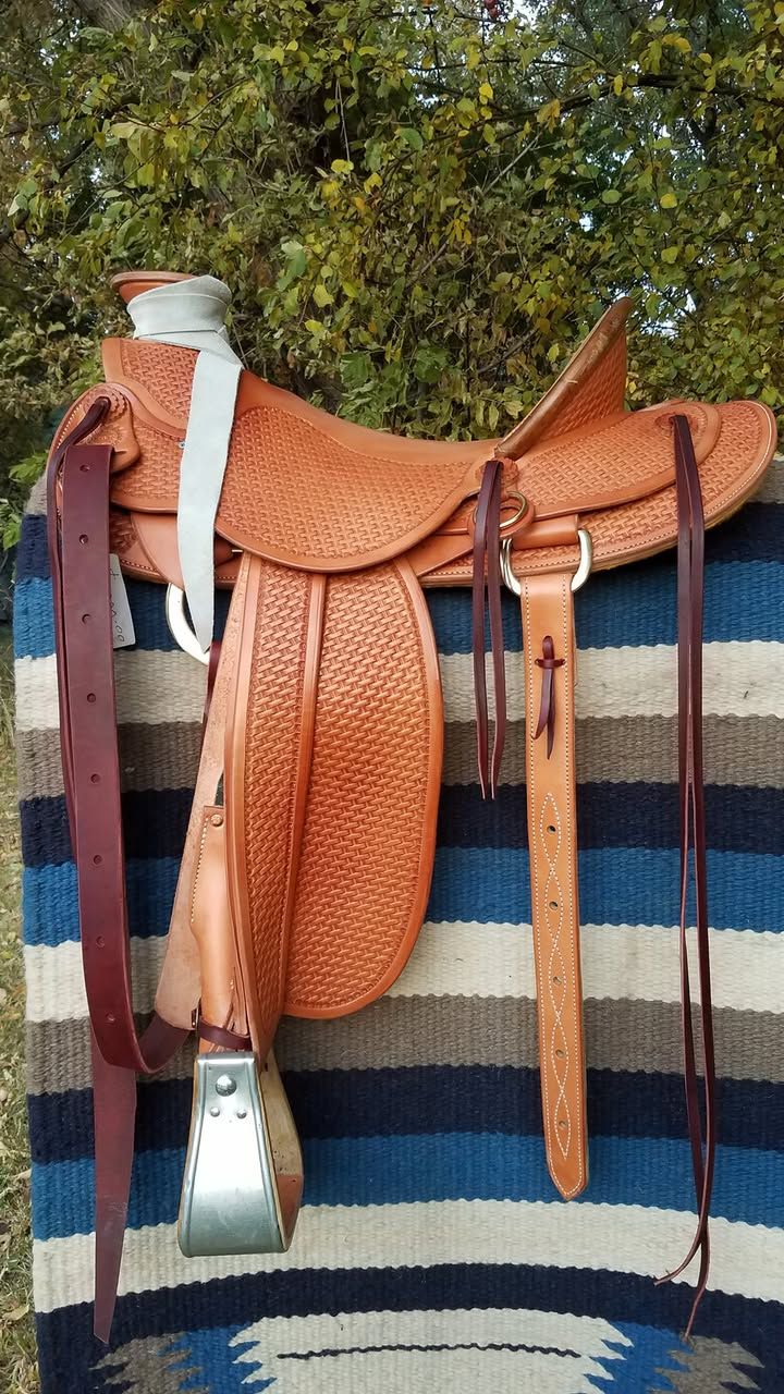 Copper-colored saddle and leather tack hanging on a striped woven rug display