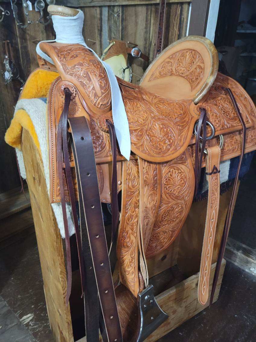 Western saddles and bridles in a wooden rack, tan and brown leather tack stored together