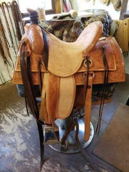 Brown leather western saddle on a stand indoors