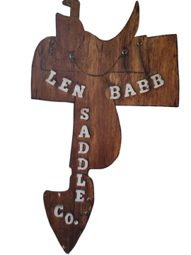 Wooden sign shaped like a fish, painted with &ldquo;LEN BABB SADDLE CO.&rdquo;