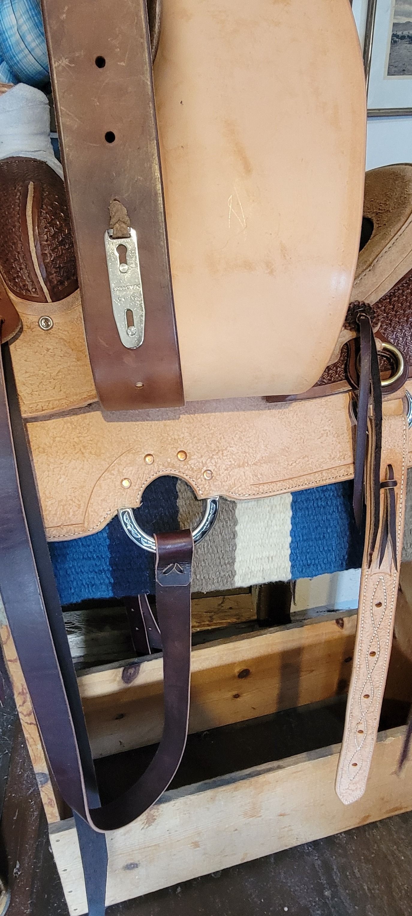 Close-up of a beige upholstered seat with straps and hardware mounted on a wooden frame.