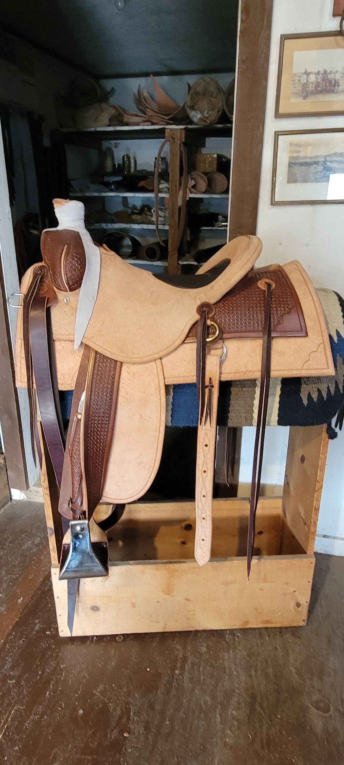 Leather saddle on a wooden stand in a dim indoor workshop