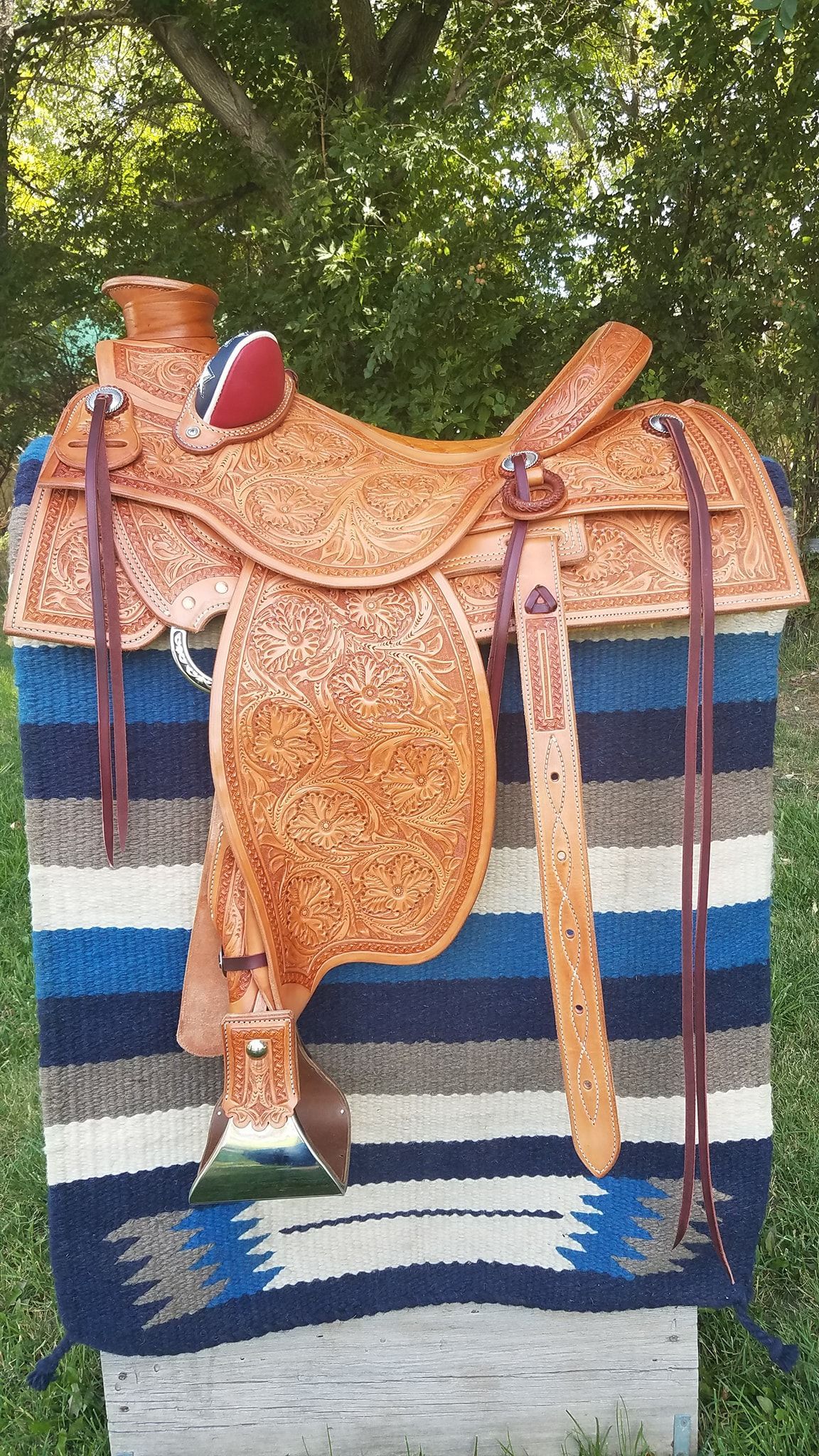 Orange saddle blanket on a woven textile backdrop with blue, white, and black stripes