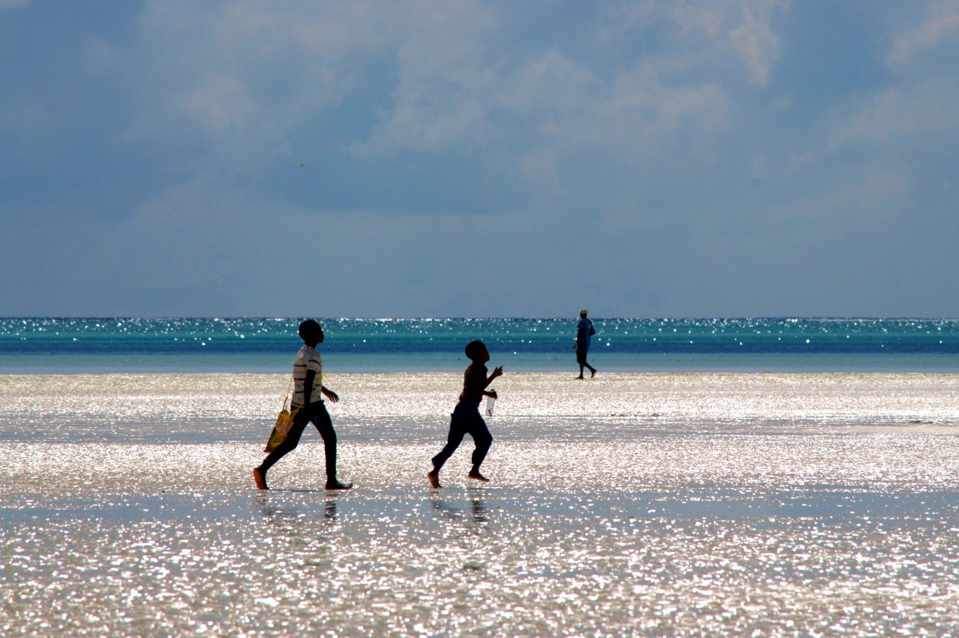 Children running joyfully to start their day of traditional fishing in Jambiani Beach, Zanzibar, Tanzania