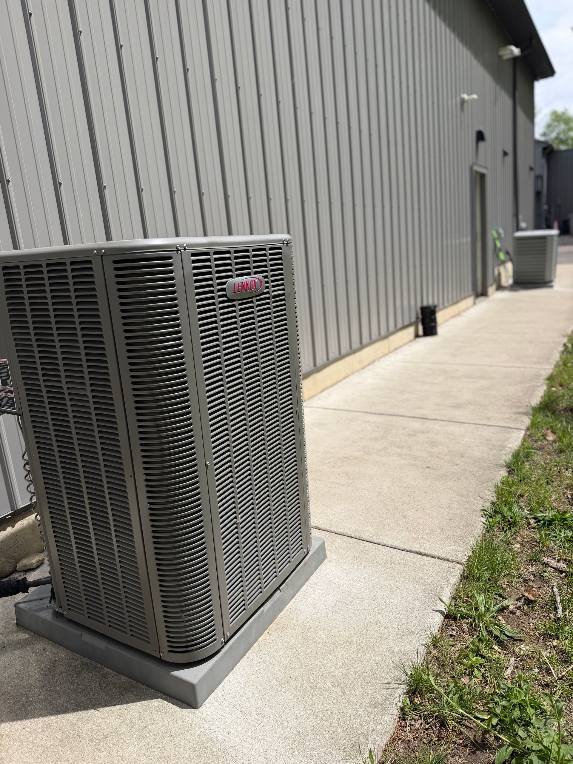 Air conditioning unit next to a white house with a deck.