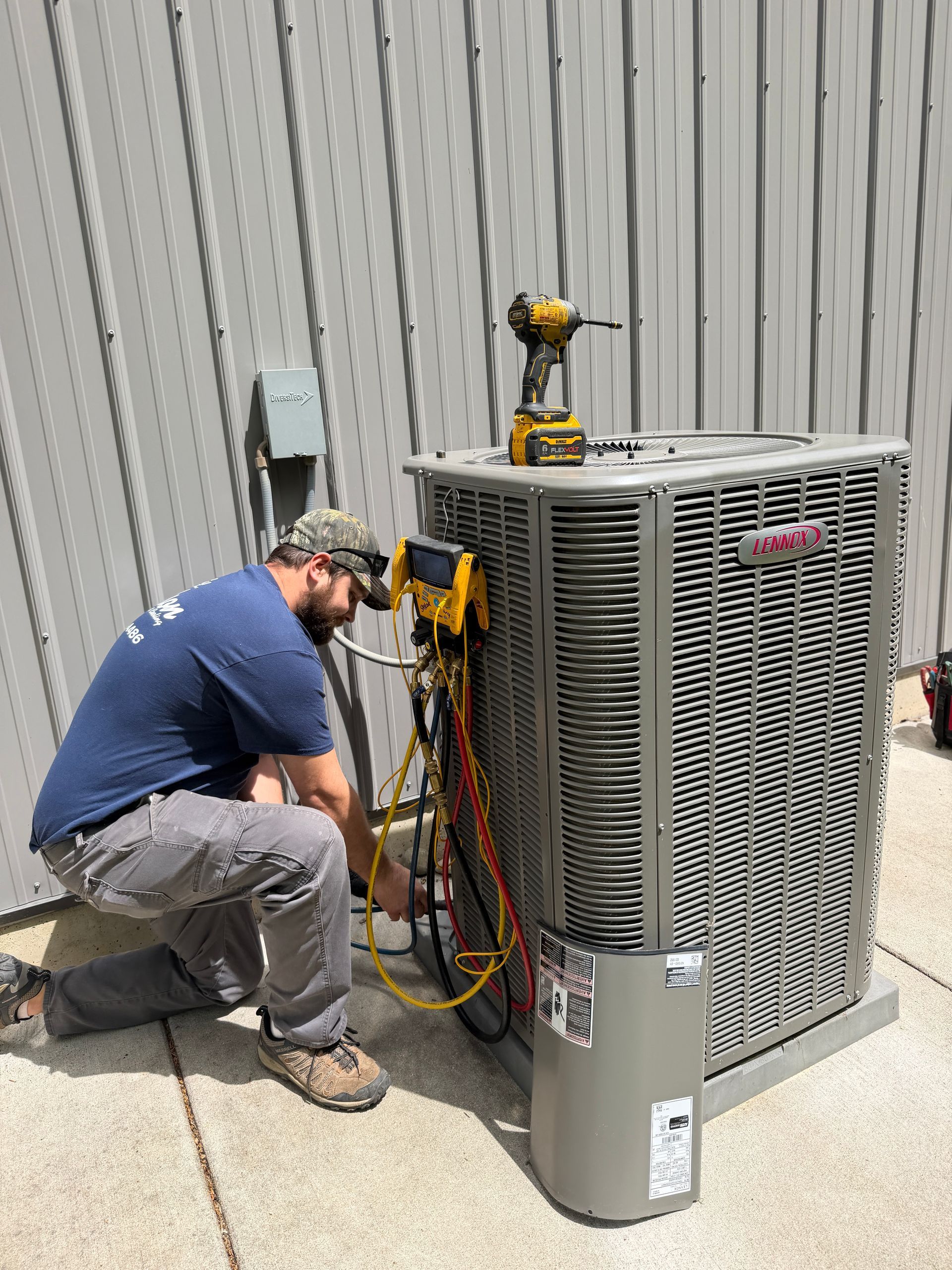 Three technicians servicing an air conditioning unit outside a building.
