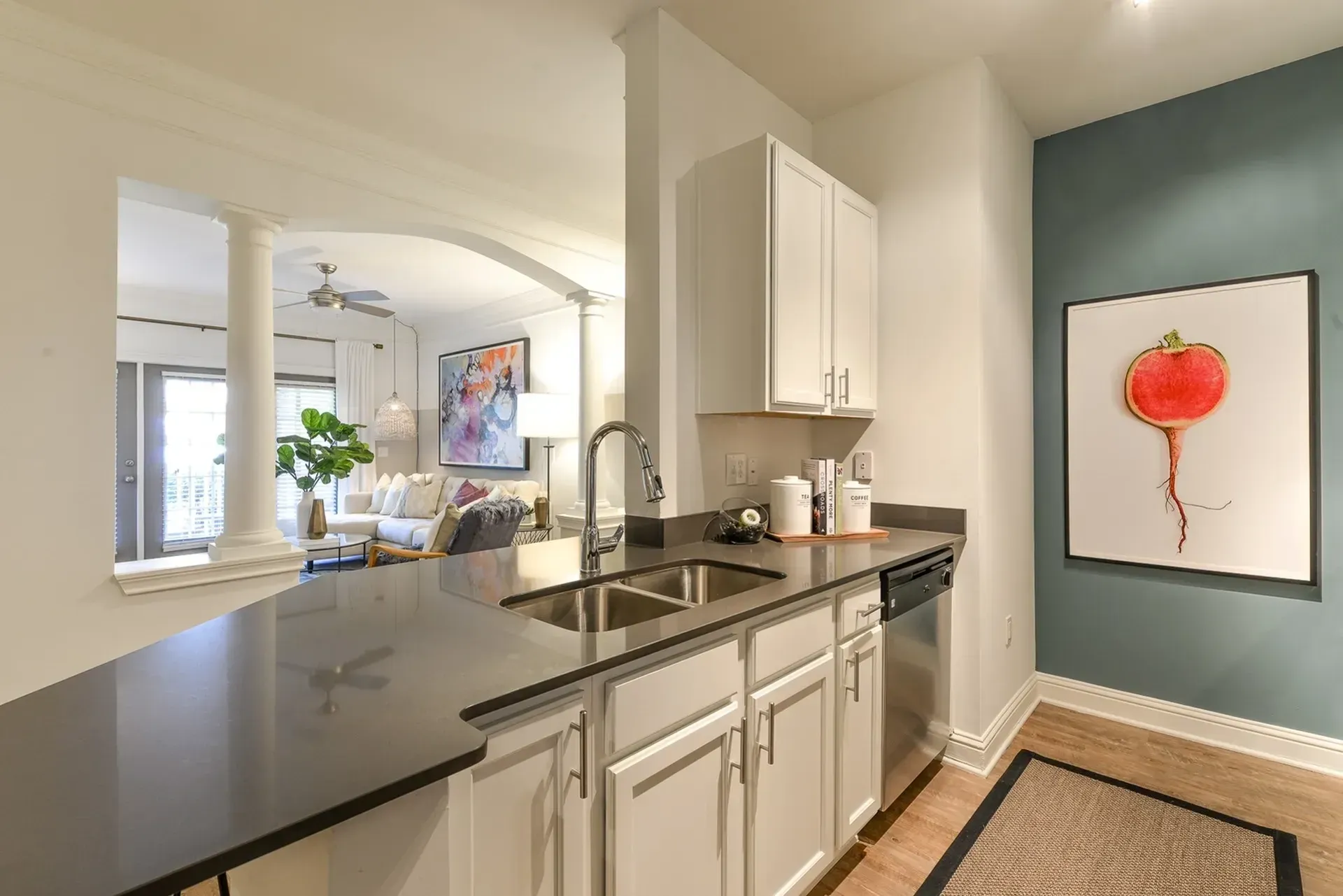 Modern kitchen with white cabinets, stainless steel appliances, and a breakfast bar opening to the living room.