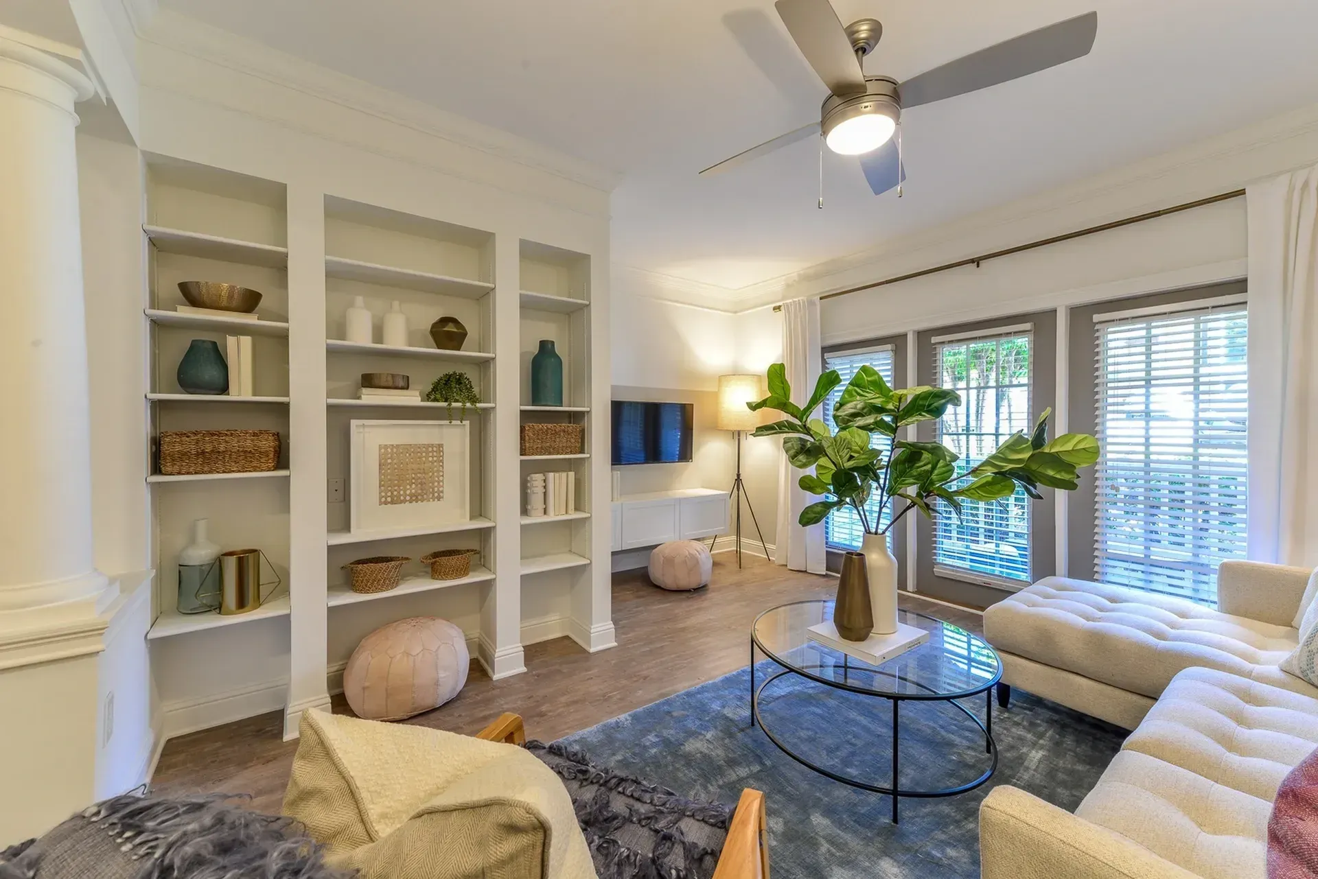 Living room with built-in bookshelves, a sectional sofa, coffee table, and a ceiling fan.