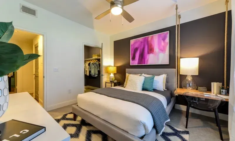 A beautifully staged bedroom with a king-sized bed, closet, and desk area.