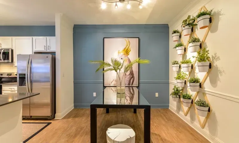 Modern dining area with a stainless steel refrigerator and vertical plant wall.