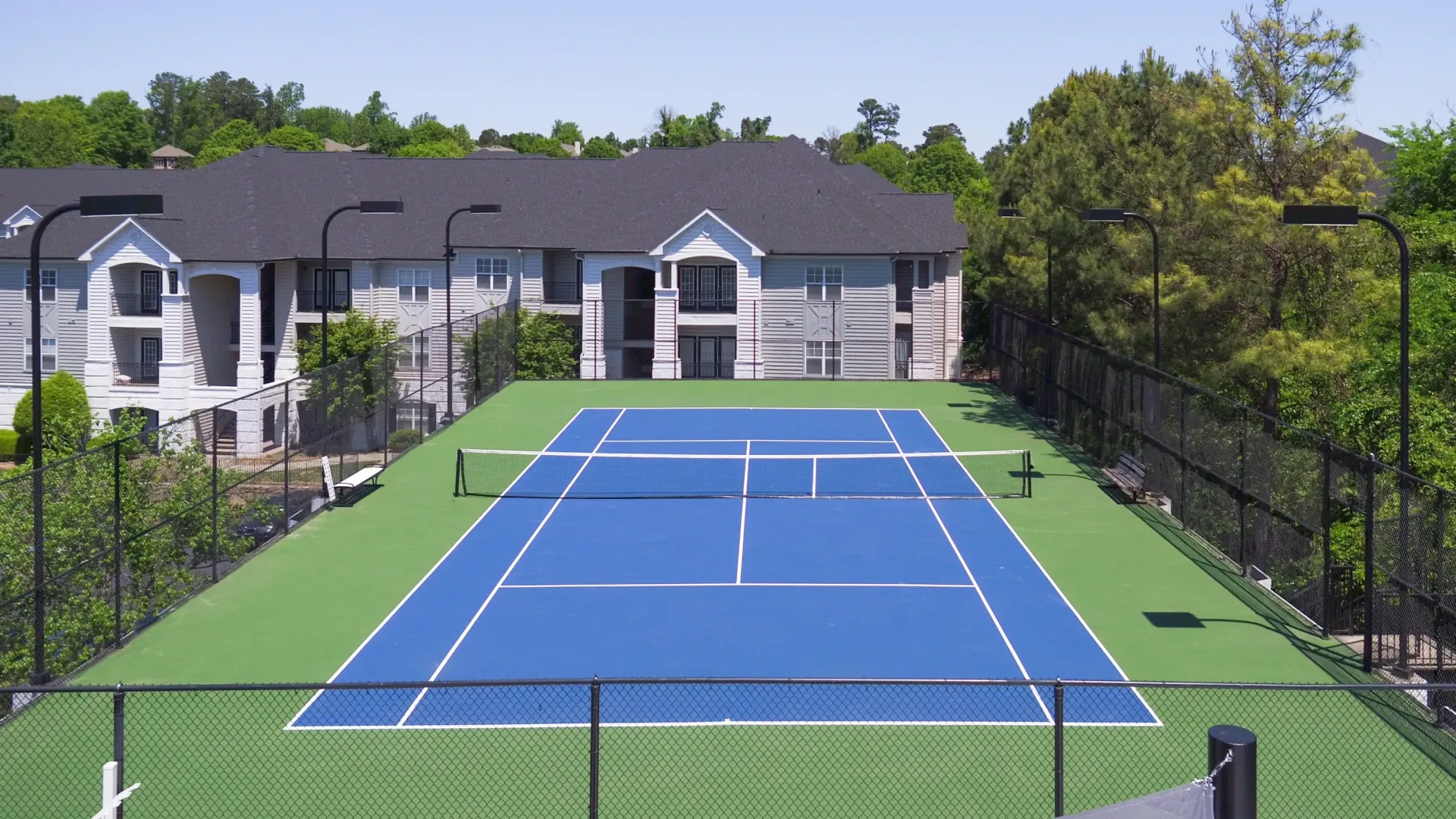 Apartment building exterior with a tennis court and net.