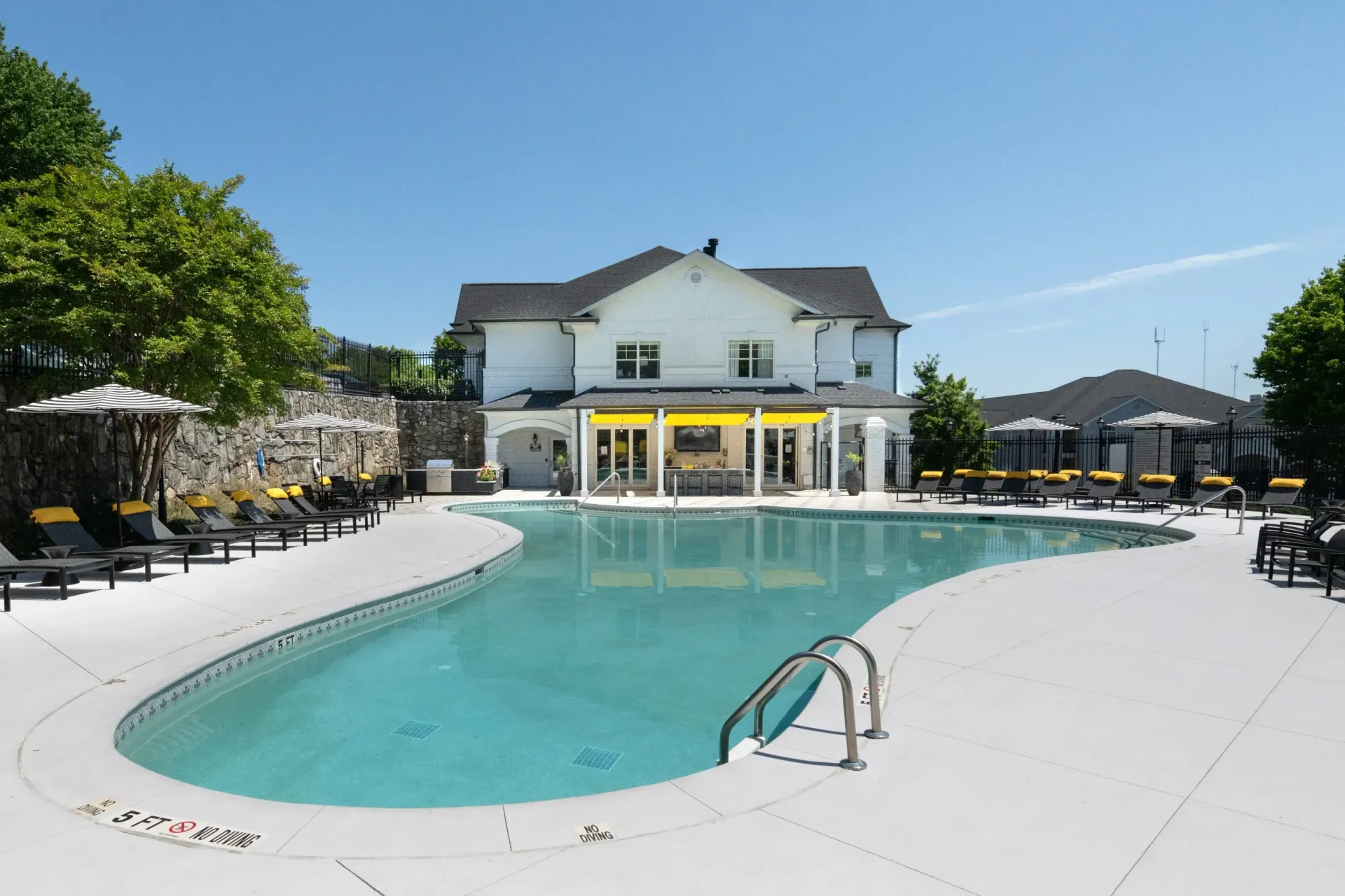Resort-style outdoor swimming pool with lounge chairs and a building in the background.