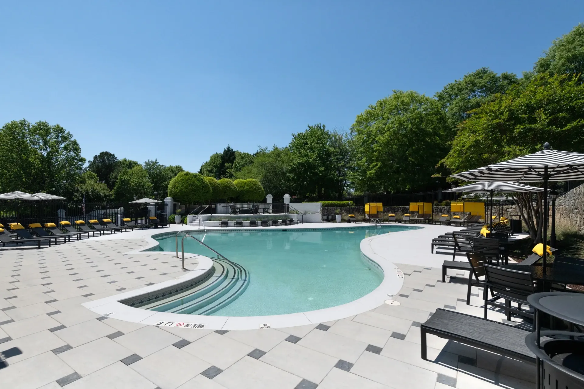 Outdoor swimming pool with lounge chairs and umbrellas.