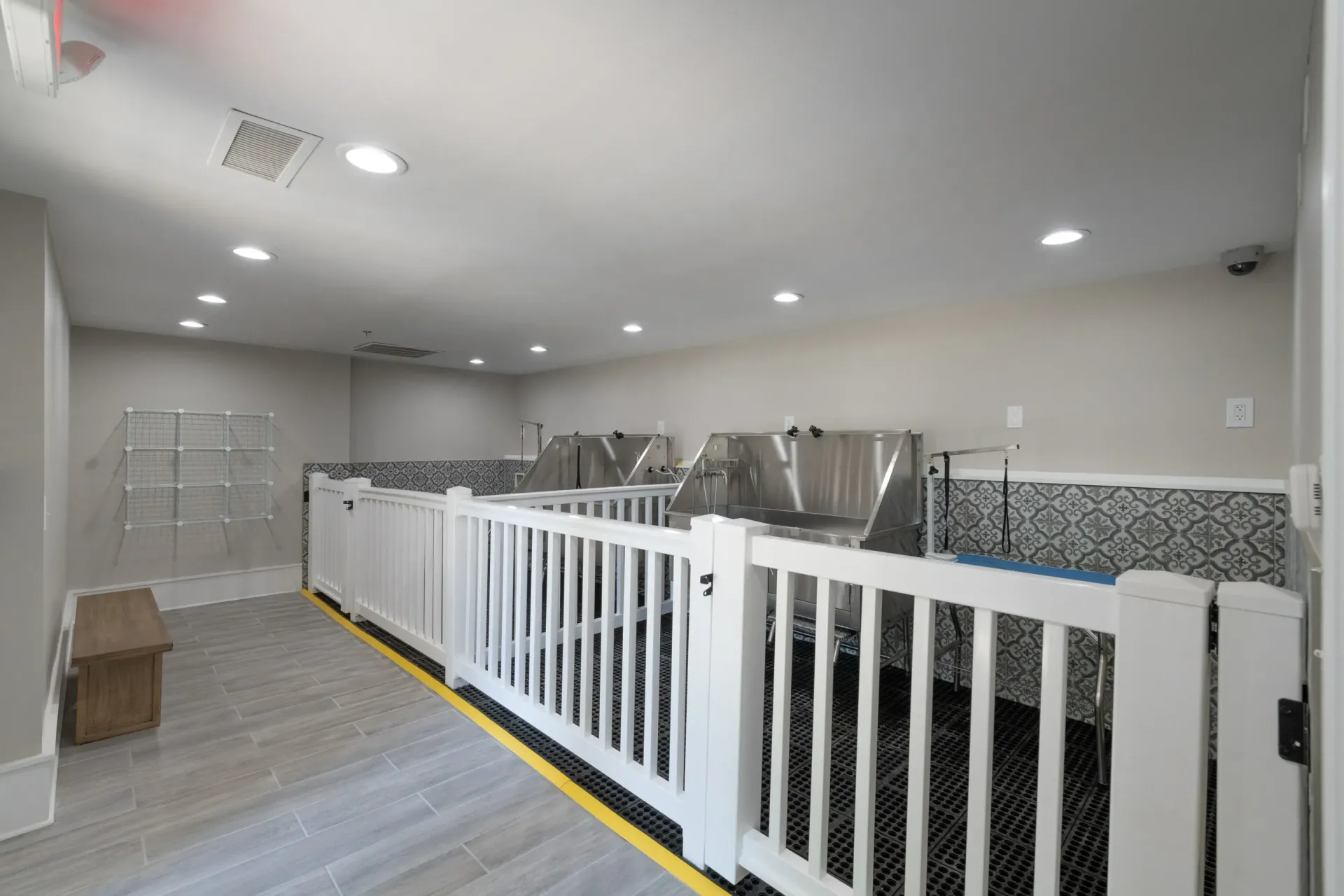 Dog grooming station with stainless steel tubs and a white railing.