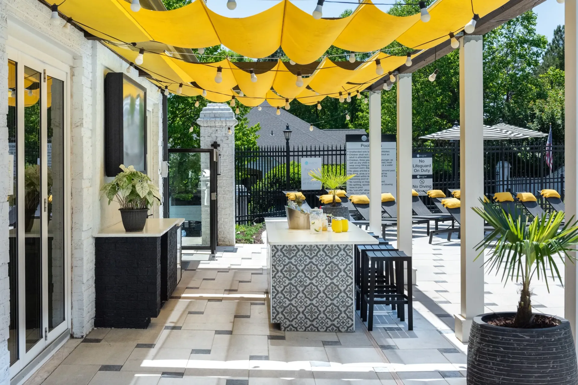 Outdoor bar area with a covered patio and pool lounge chairs in the background.