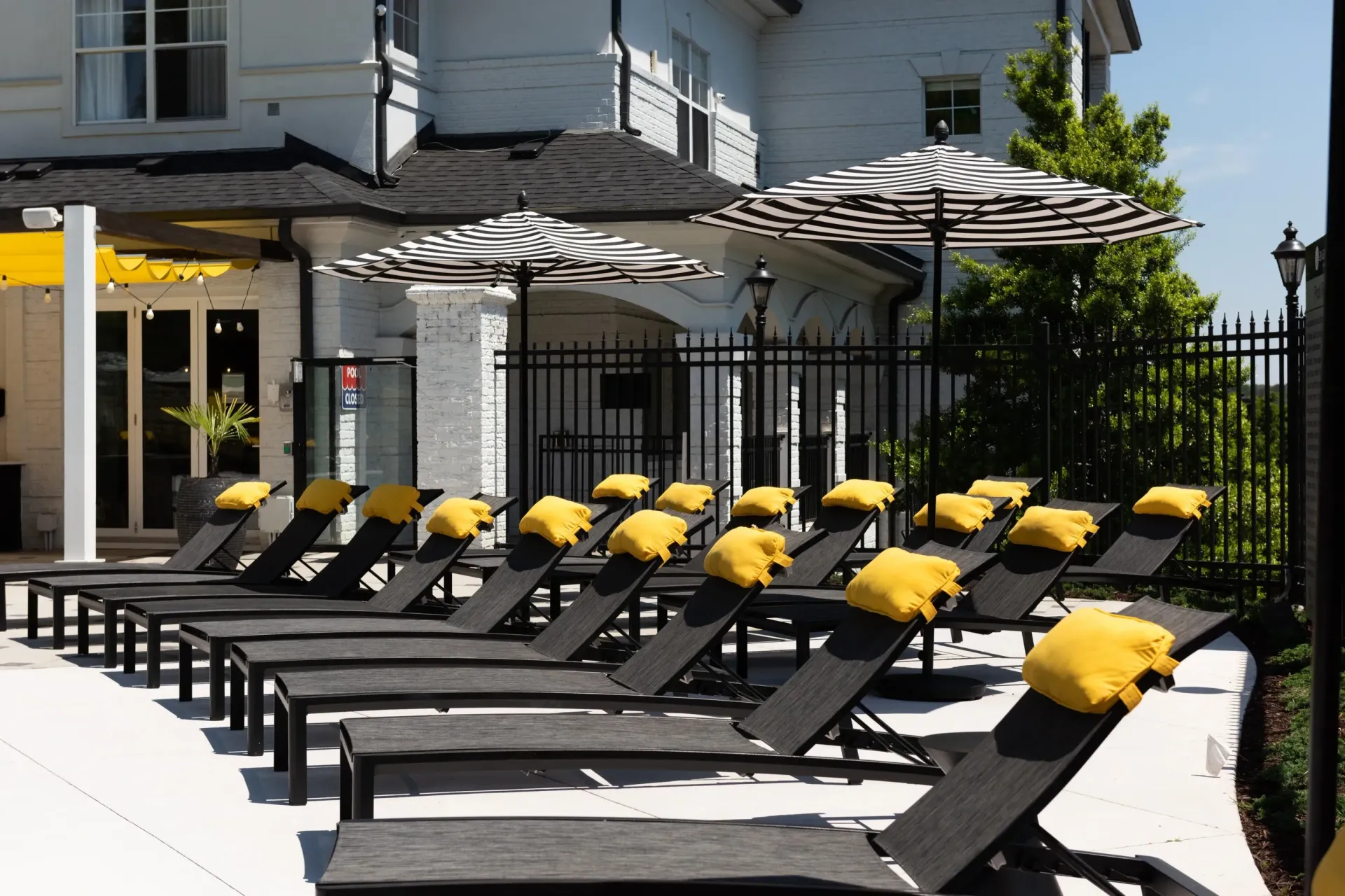 Resort-style lounge chairs with yellow cushions and striped umbrellas by the pool.