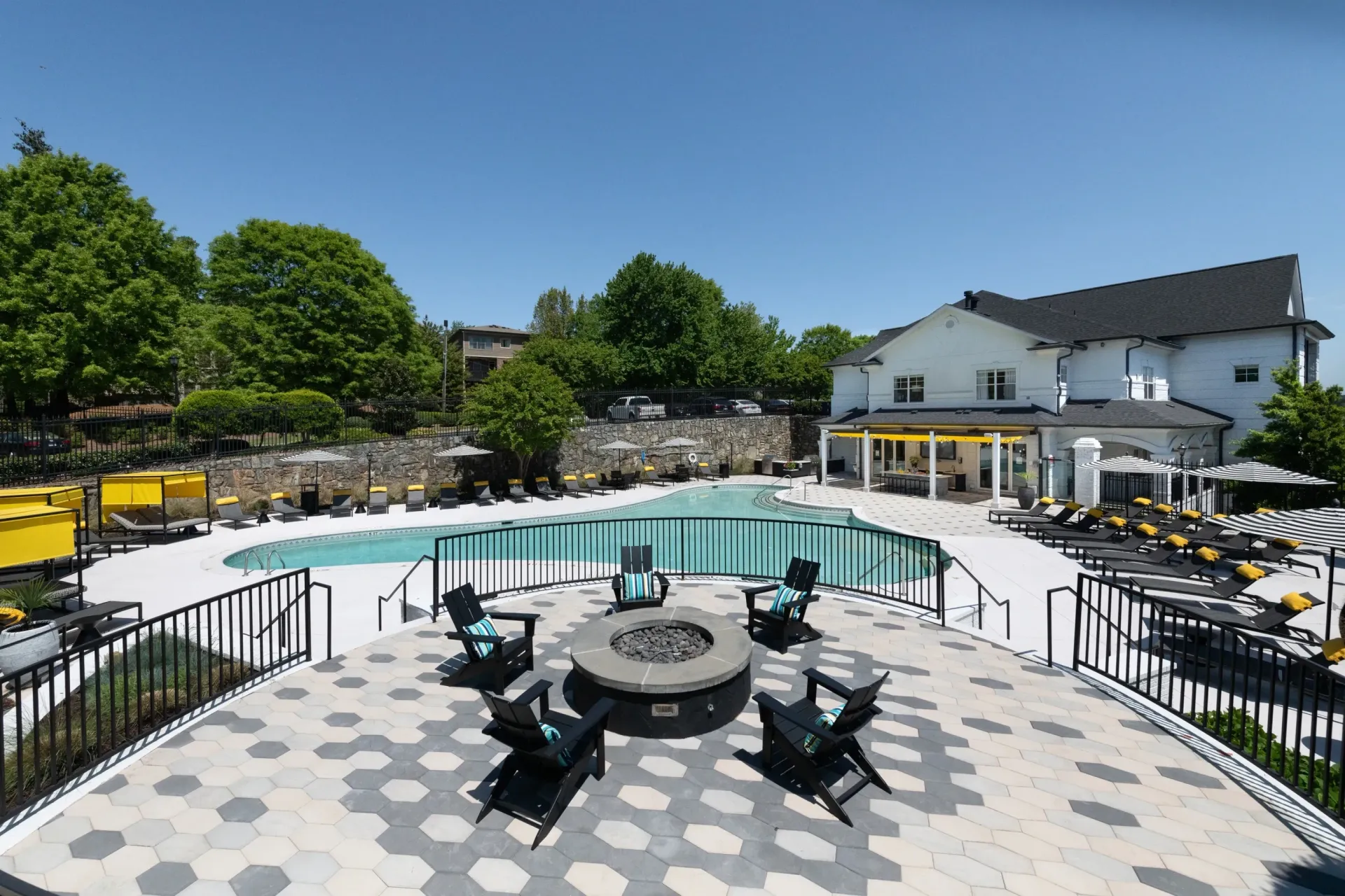 Resort-style swimming pool with lounge chairs and a fire pit area.