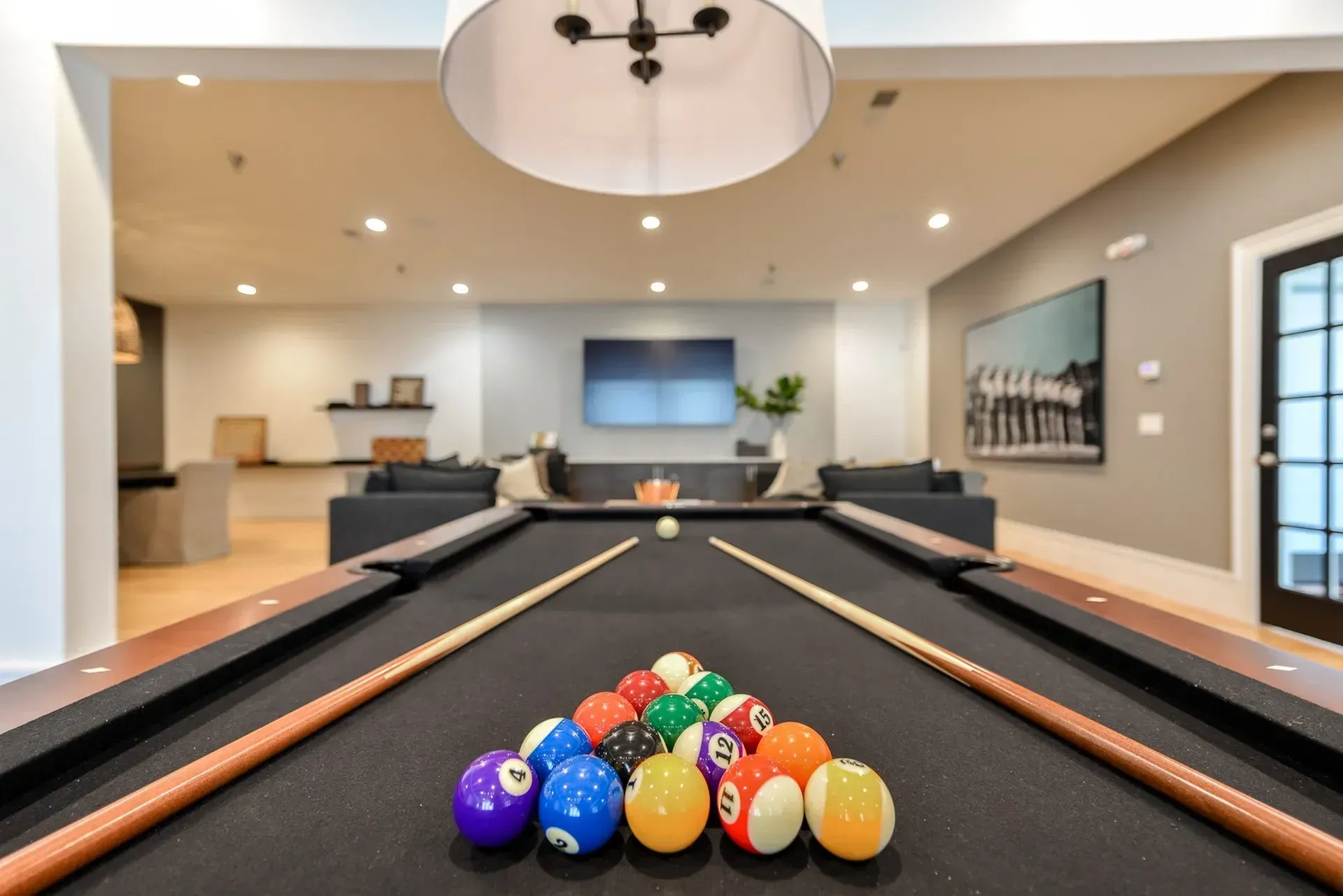 Billiards table in a resident lounge with seating and a large TV.