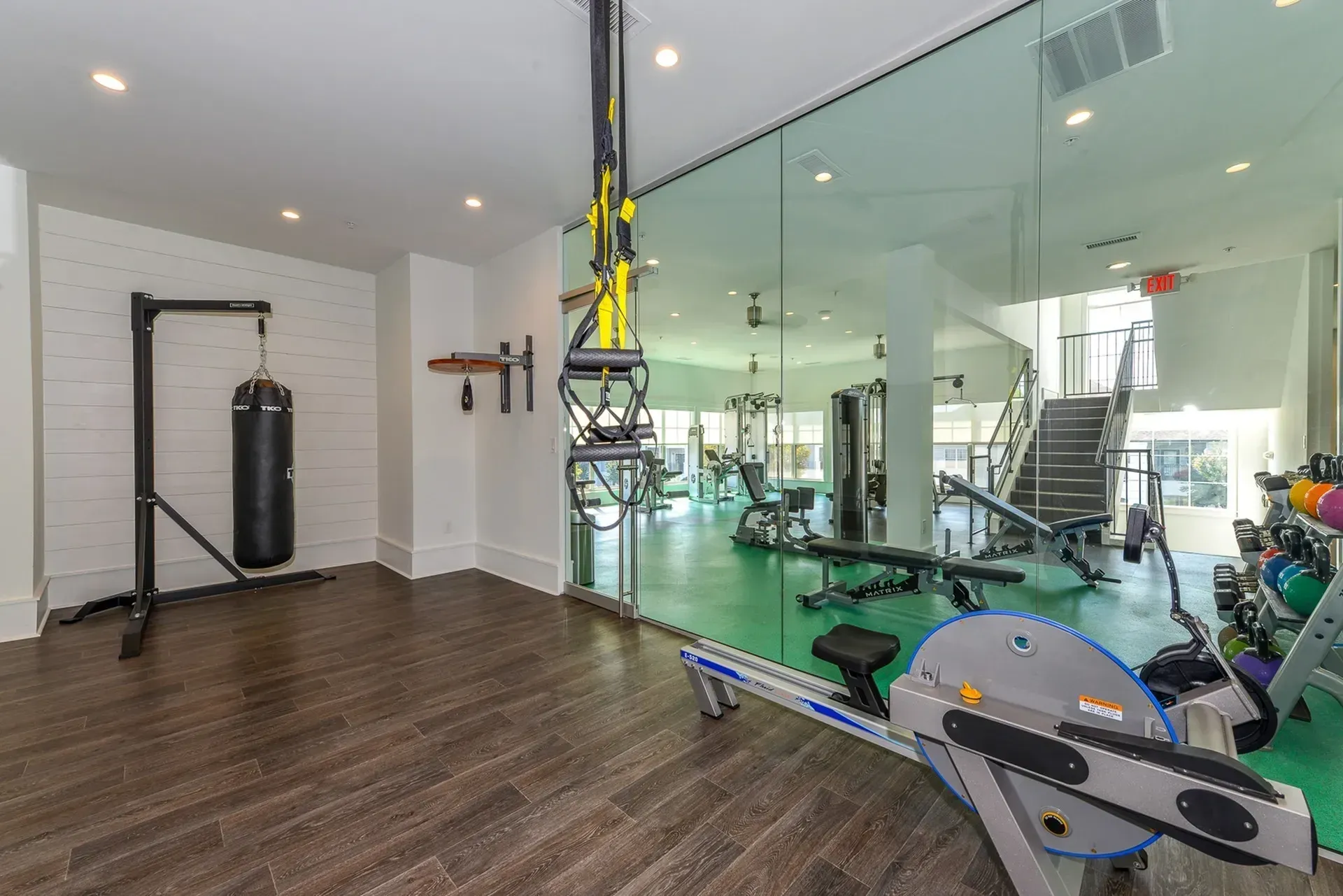 Gym with punching bag, rowing machine, weights, and cardio equipment.