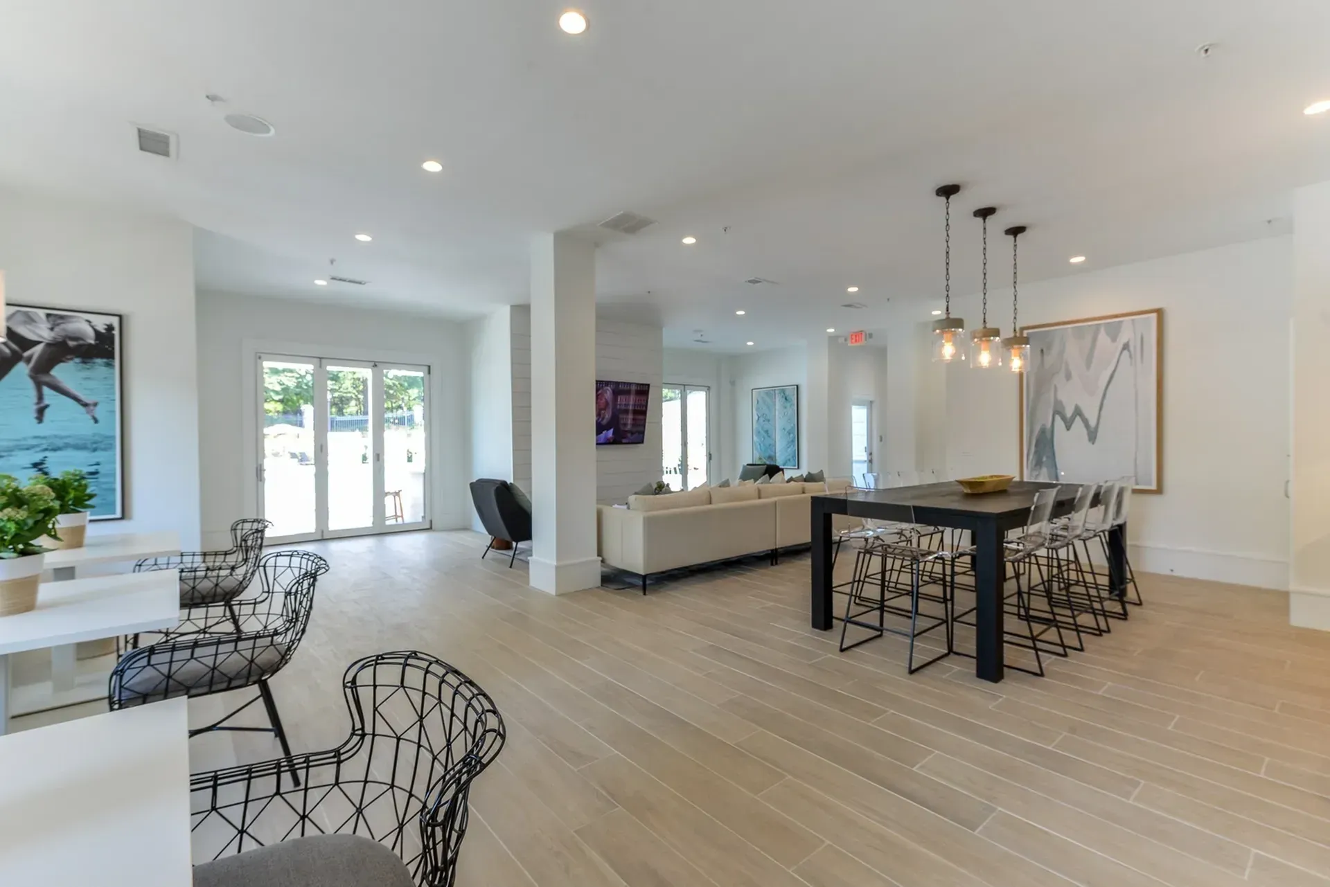 Modern community lounge with large windows, comfortable seating, and a communal dining table.