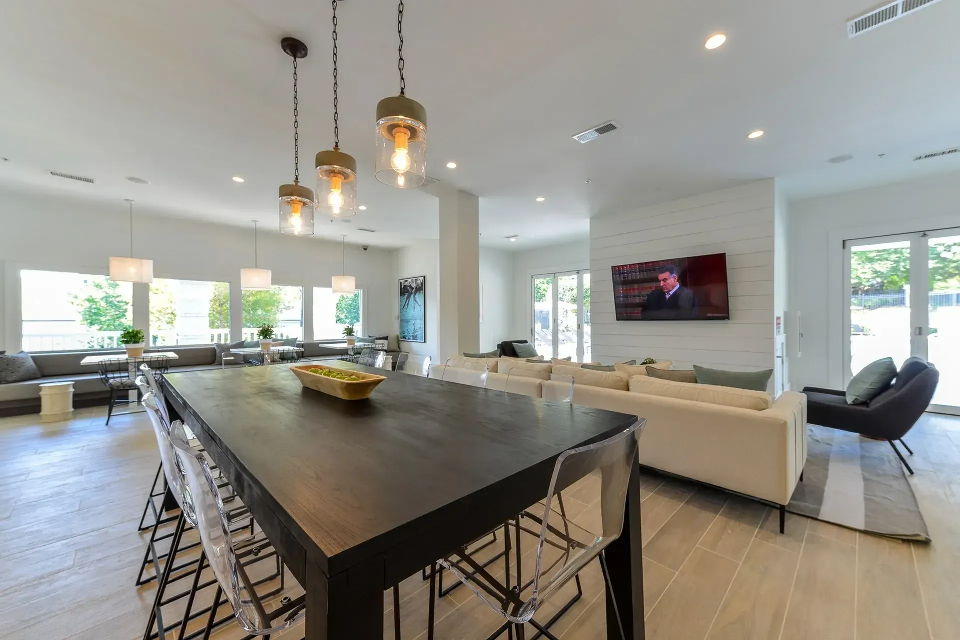 Modern lounge area with a long dining table, comfortable seating, and a television.