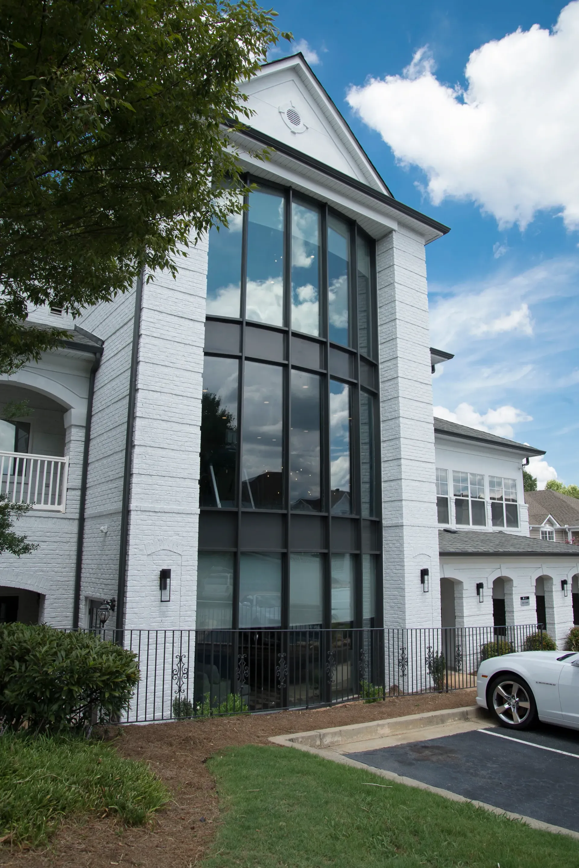 Exterior of a multifamily property with large windows and a white brick facade.