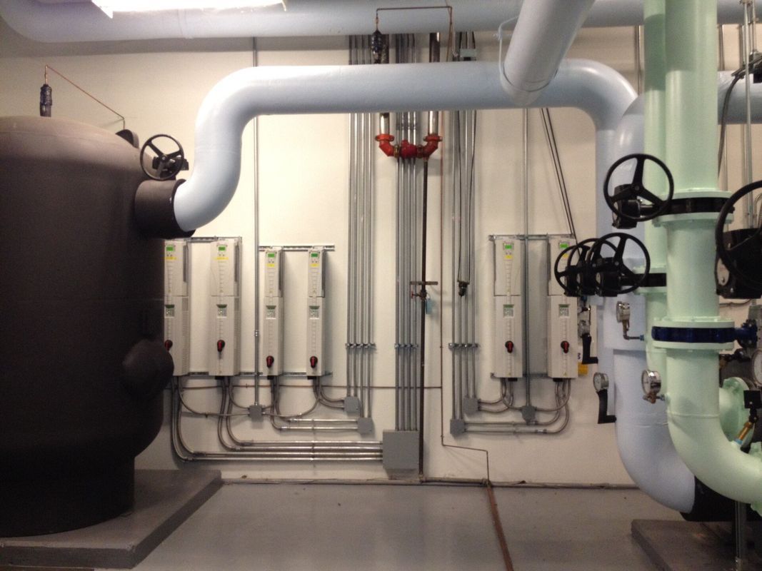 Industrial room with pipes, valves, and electrical boxes against a wall.