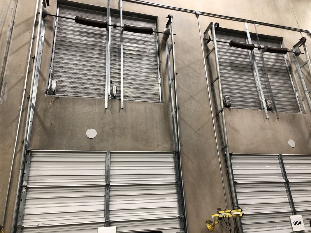 Exterior of a warehouse with two loading docks, each with a closed metal roll-up door.
