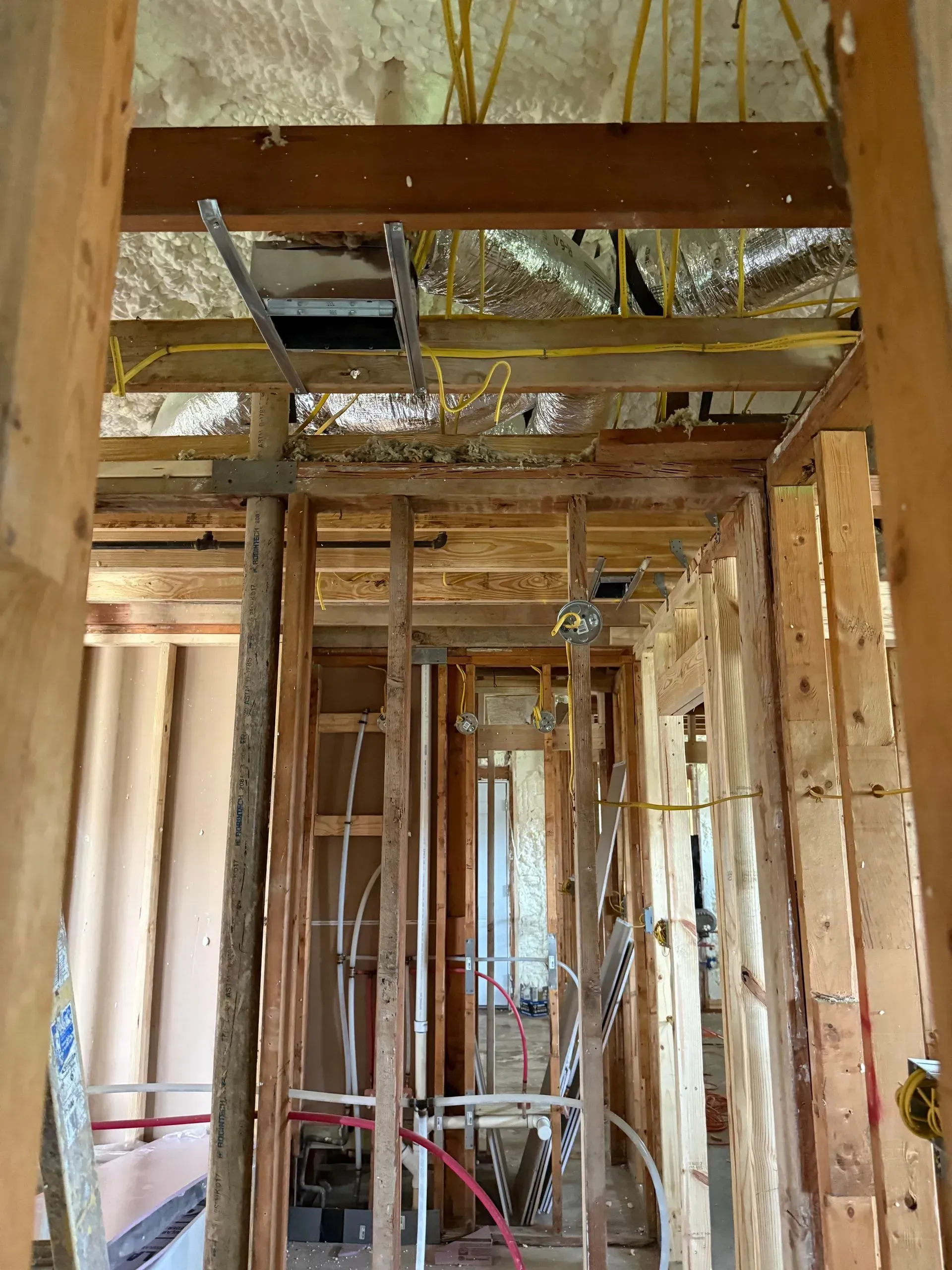 Interior of a house under renovation with exposed wooden framing and open wall cavities