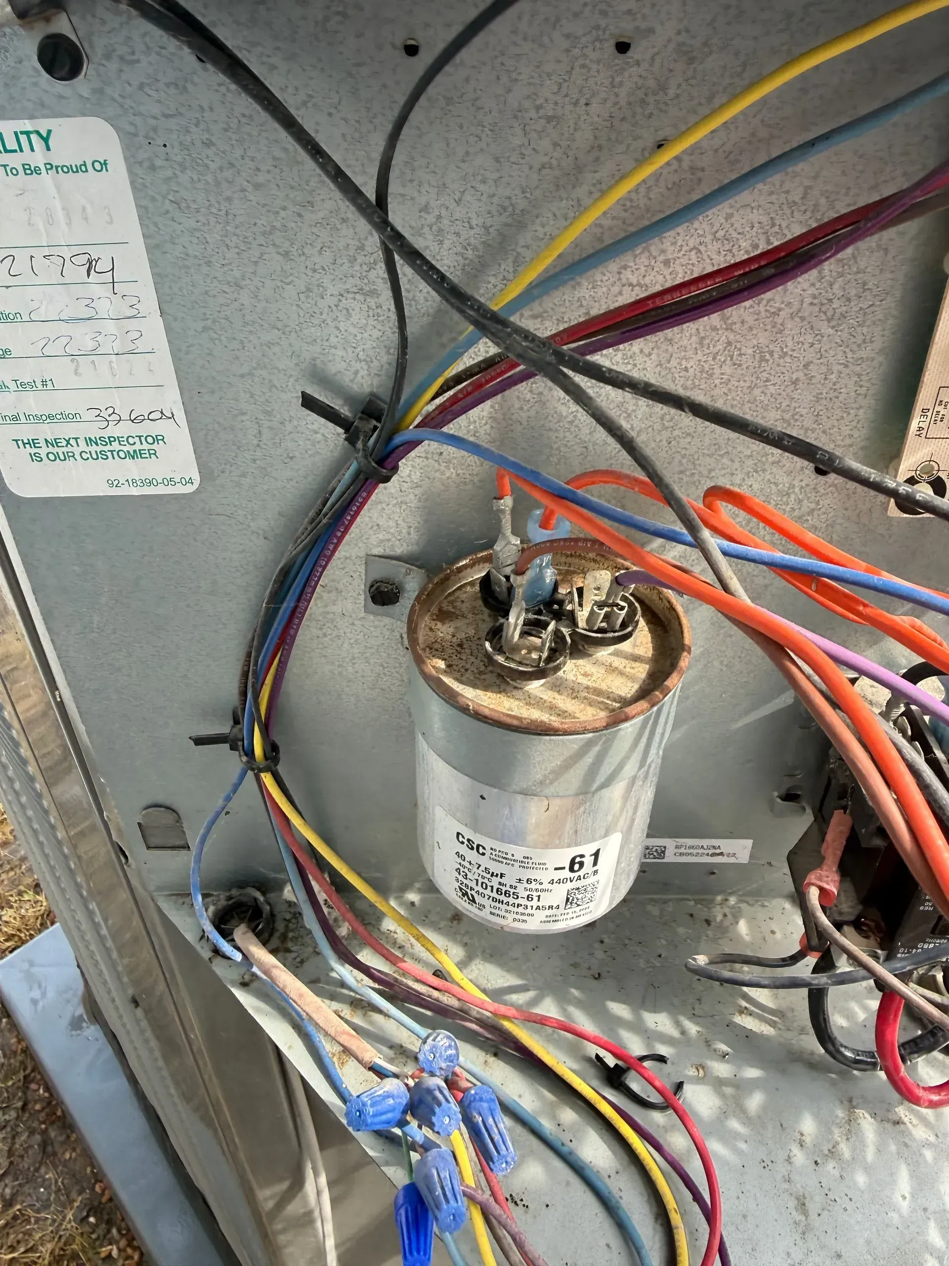 Electrical equipment panel with a capacitor and bundled multicolored wires inside a metal enclosure