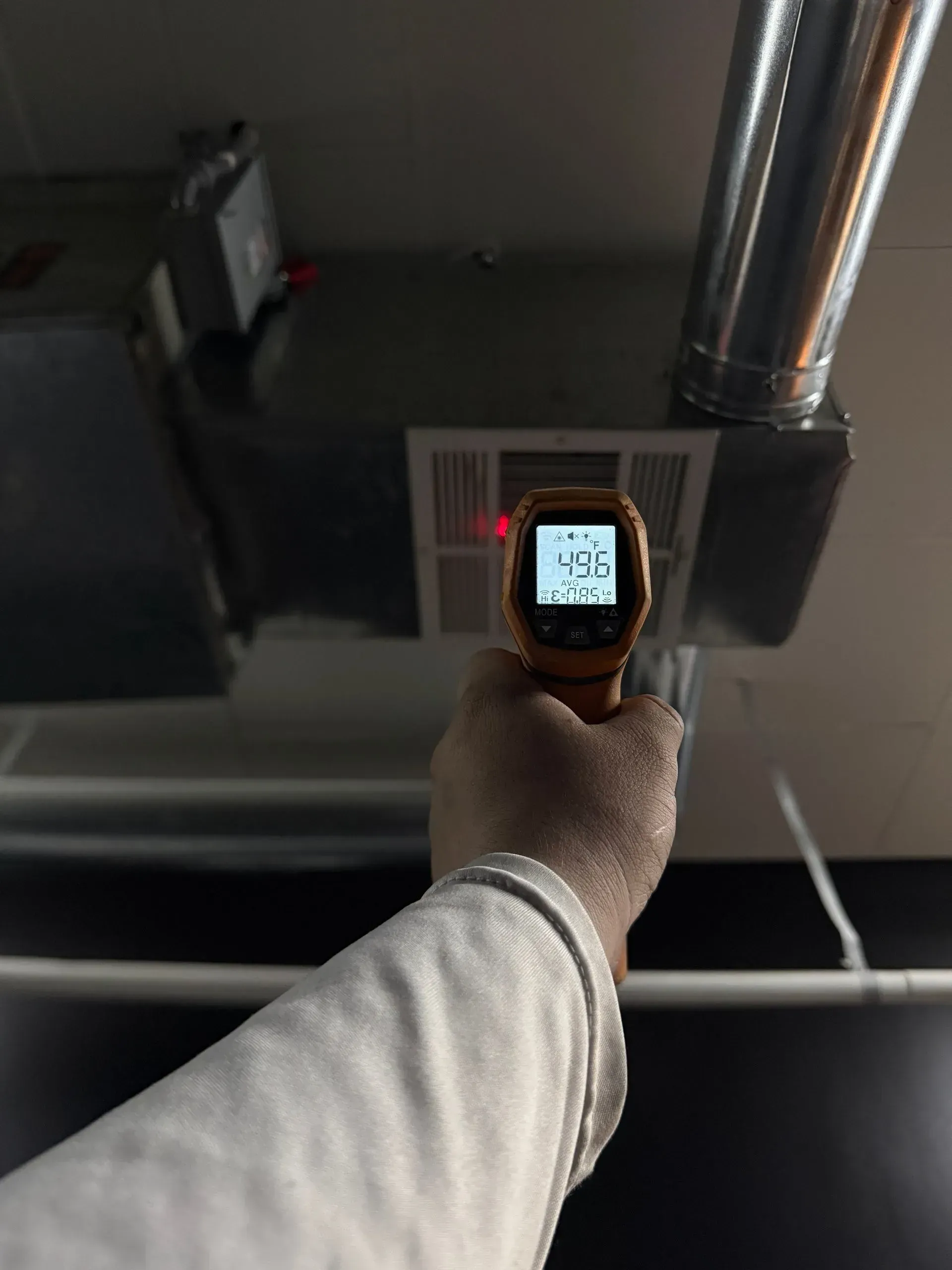 Hand holding a thermal camera toward a ceiling vent, displaying 19.6°F.