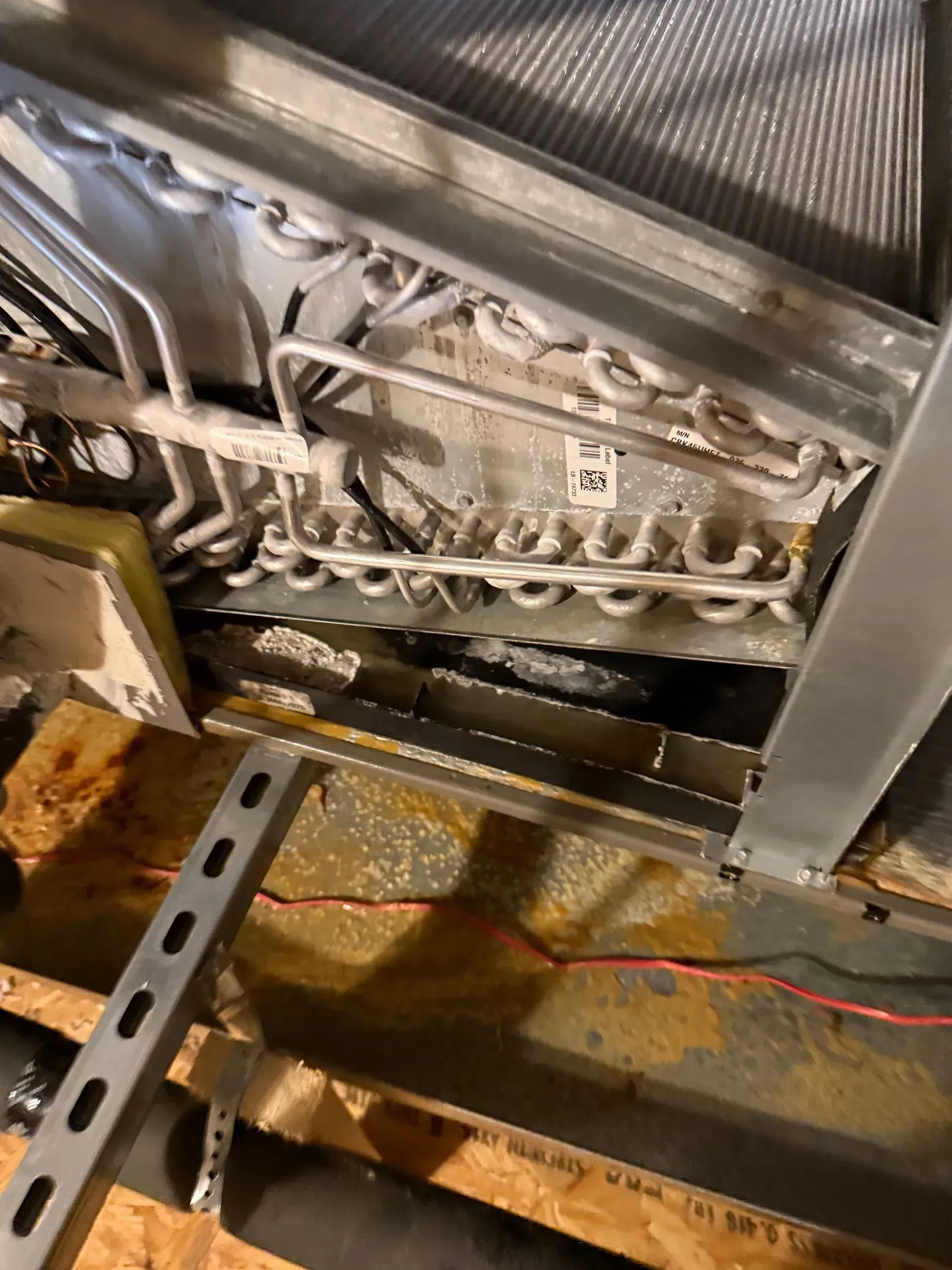 Close-up of a dirty industrial machine belt and metal frame with rust and debris.