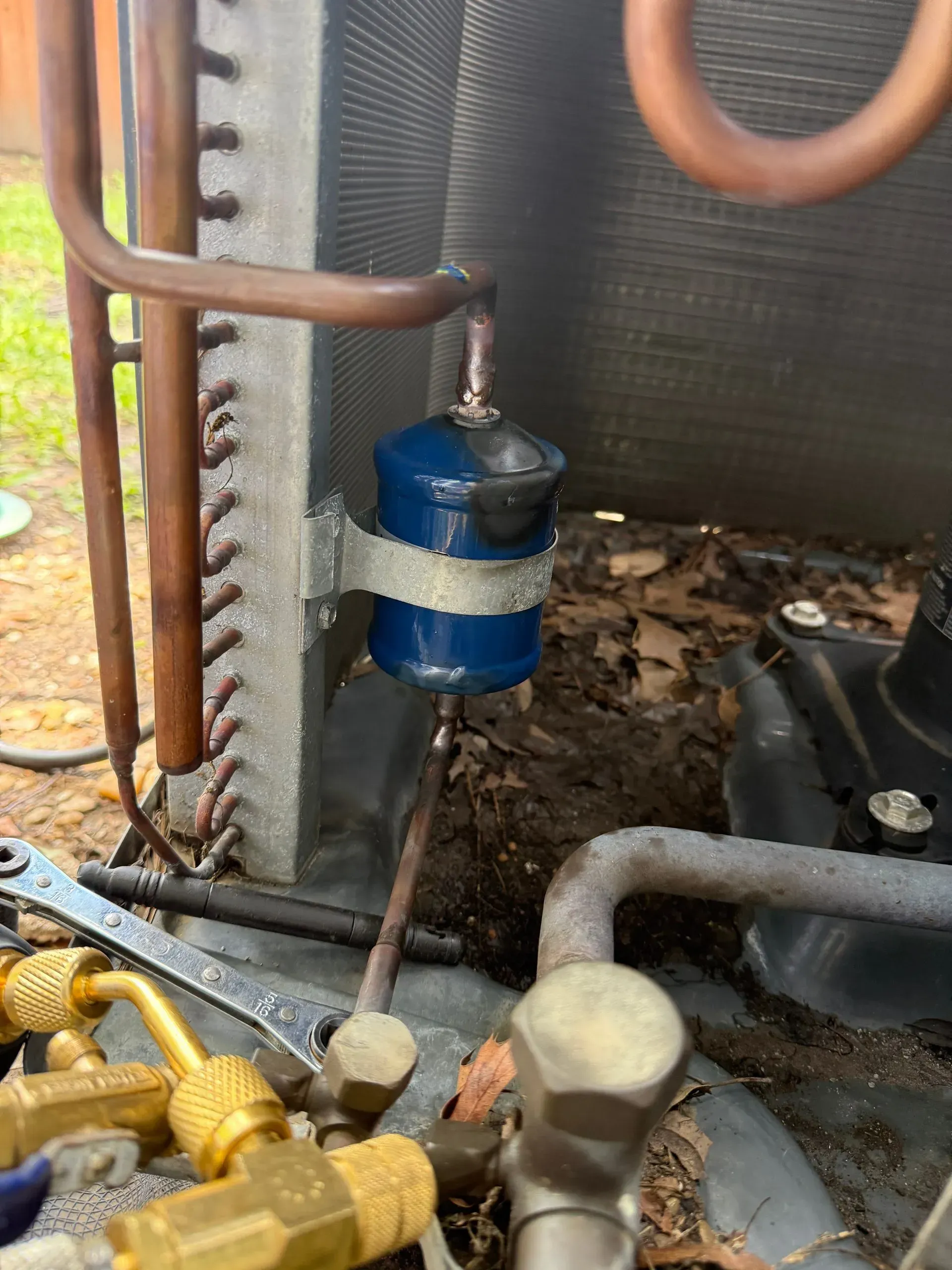 Blue cylindrical component among copper pipes in an industrial HVAC unit.