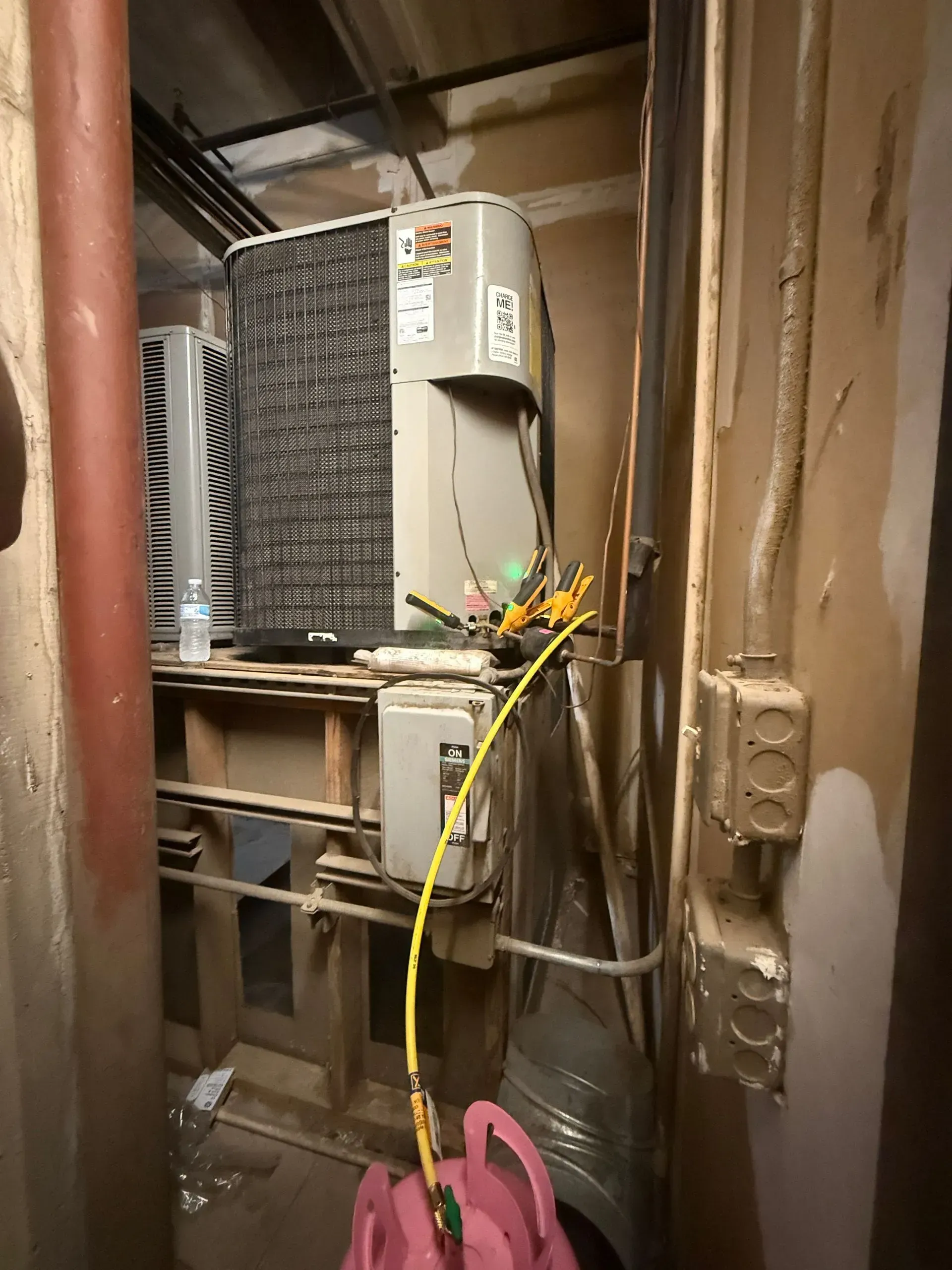 Industrial electrical equipment in a narrow utility closet with exposed wiring and pipes