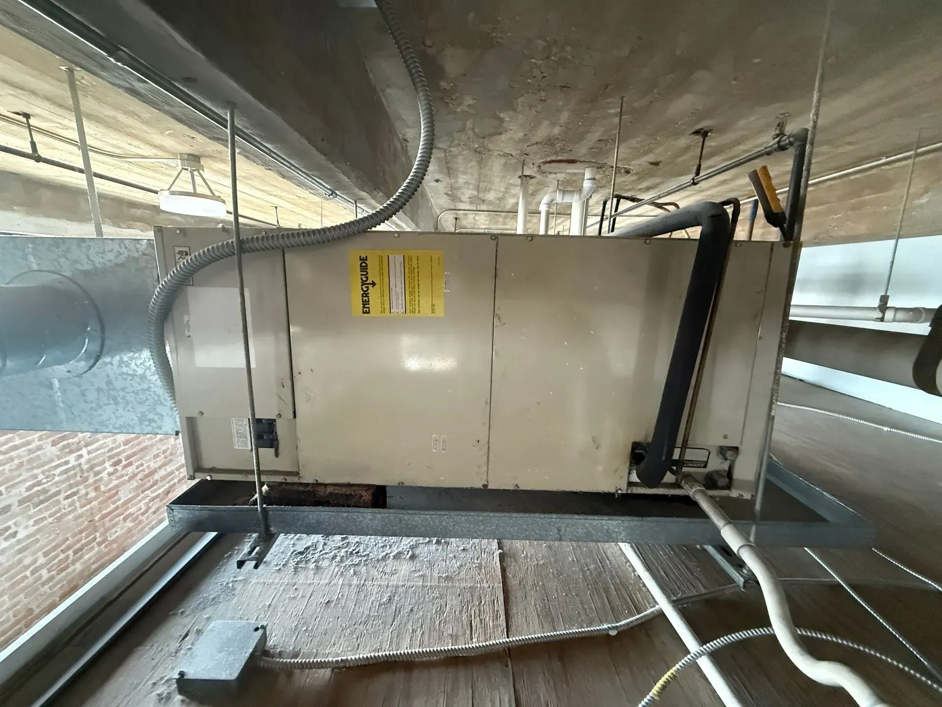 Large HVAC unit in a ceiling crawlspace with ducts and metal framing