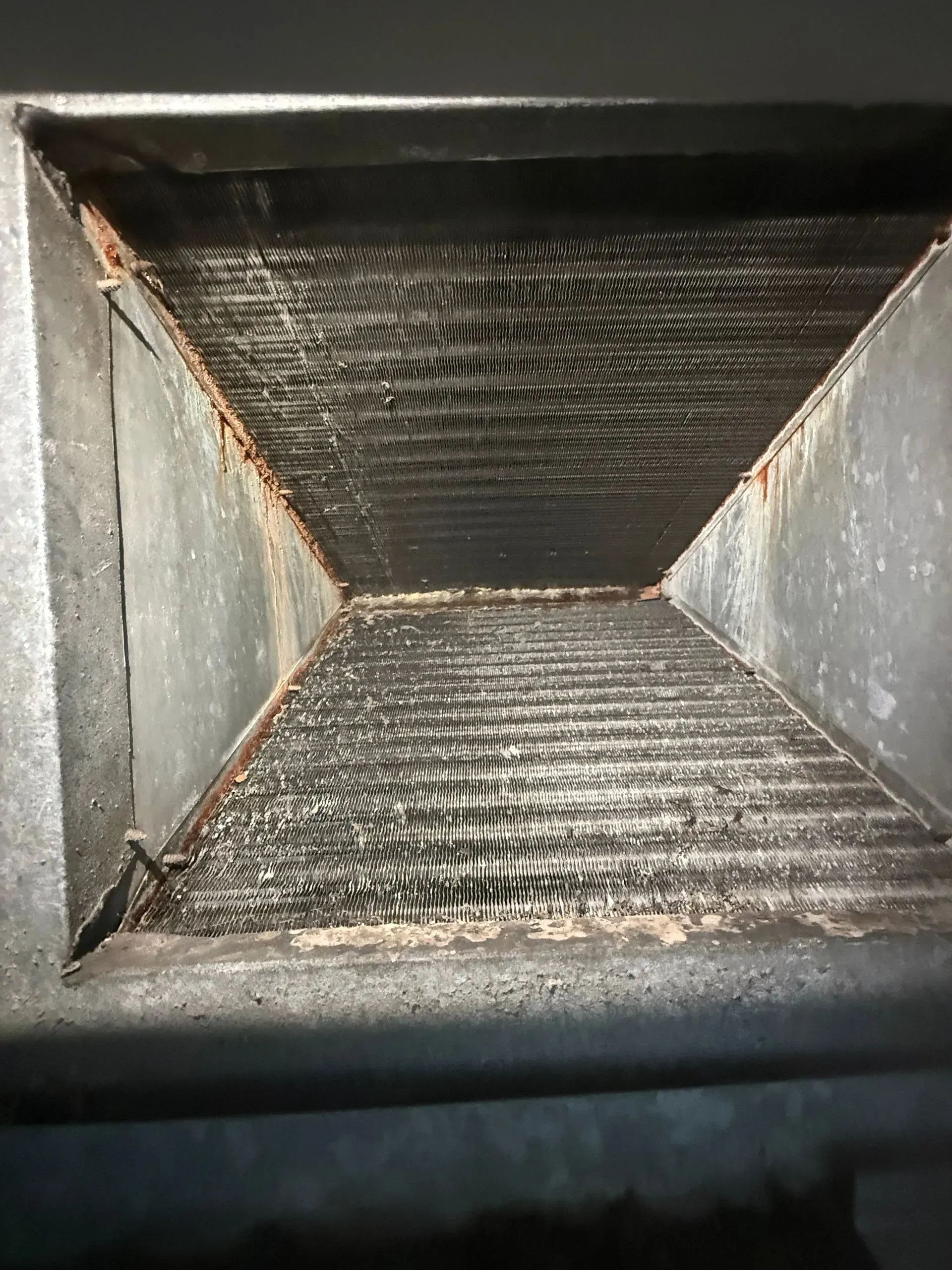 Empty rectangular duct interior with black ribbed walls and a dusty bottom panel.