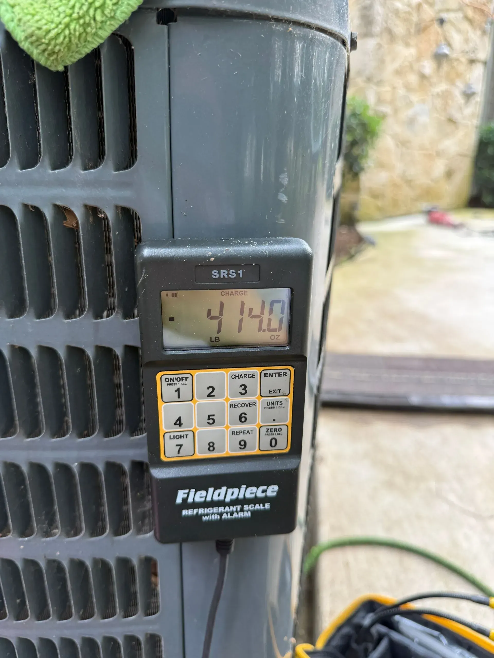 Keypad lock on a black outdoor unit with a small display and yellow buttons