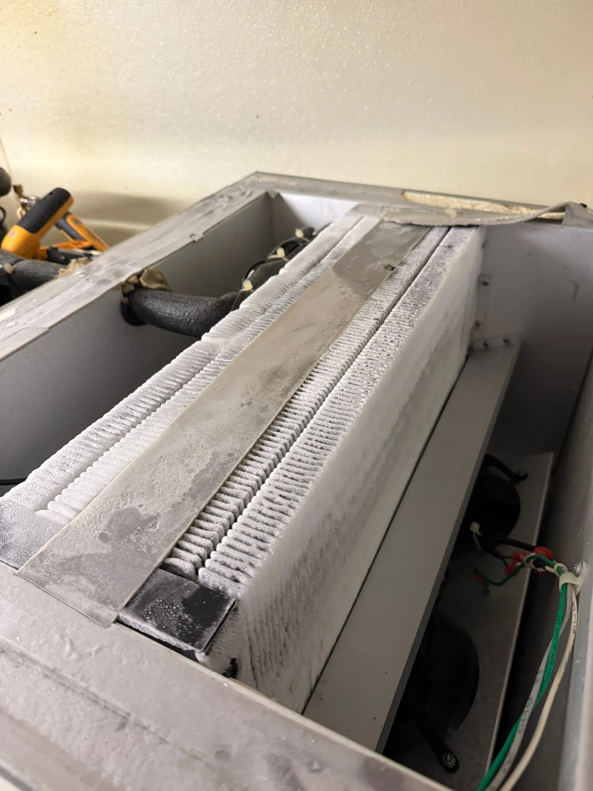 Close-up of a dusty attic HVAC vent and ductwork with exposed wiring.