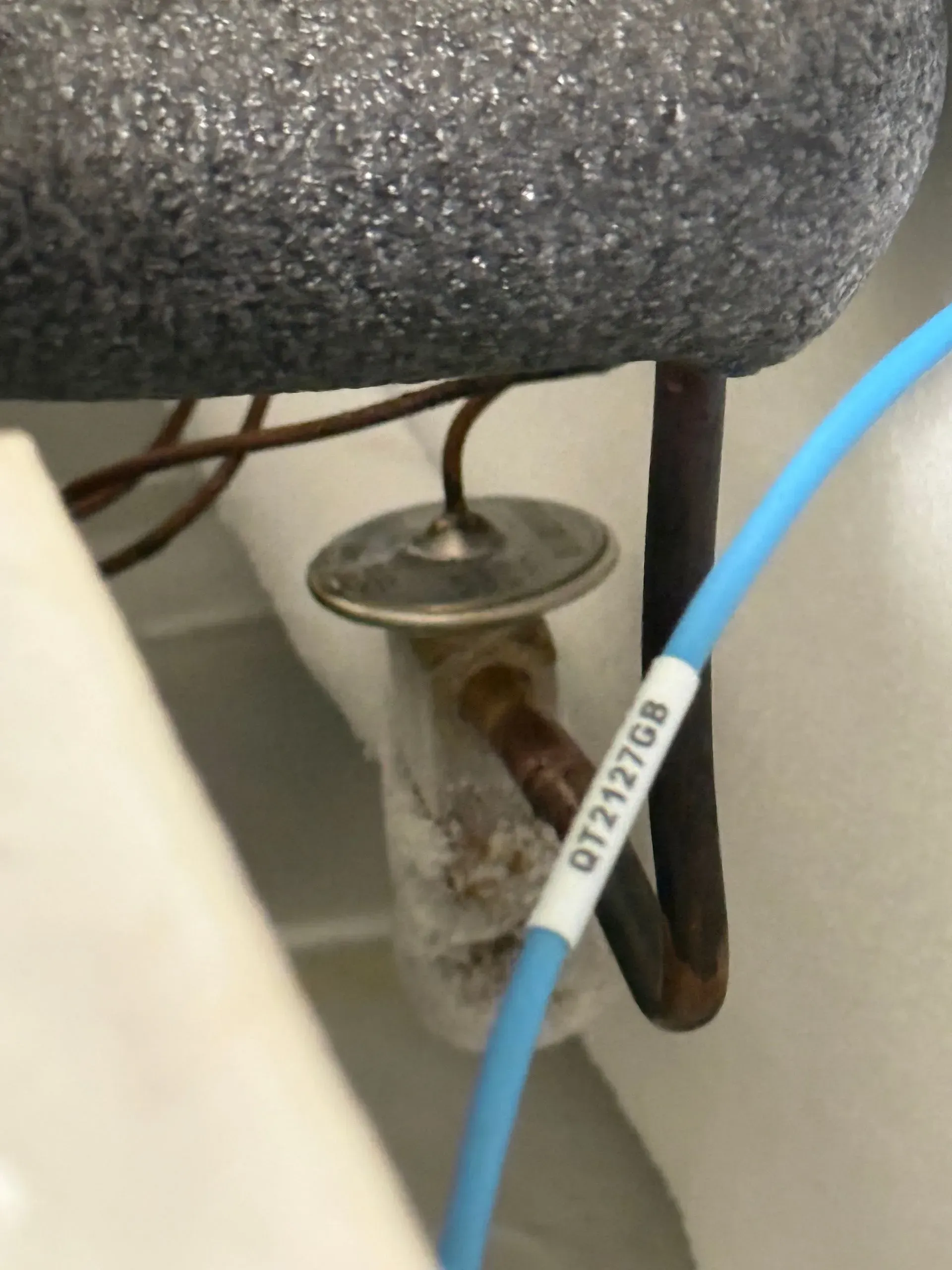 Blue cable labeled “DTTF10” beside a metal desk leg and chair wheel on a carpeted floor