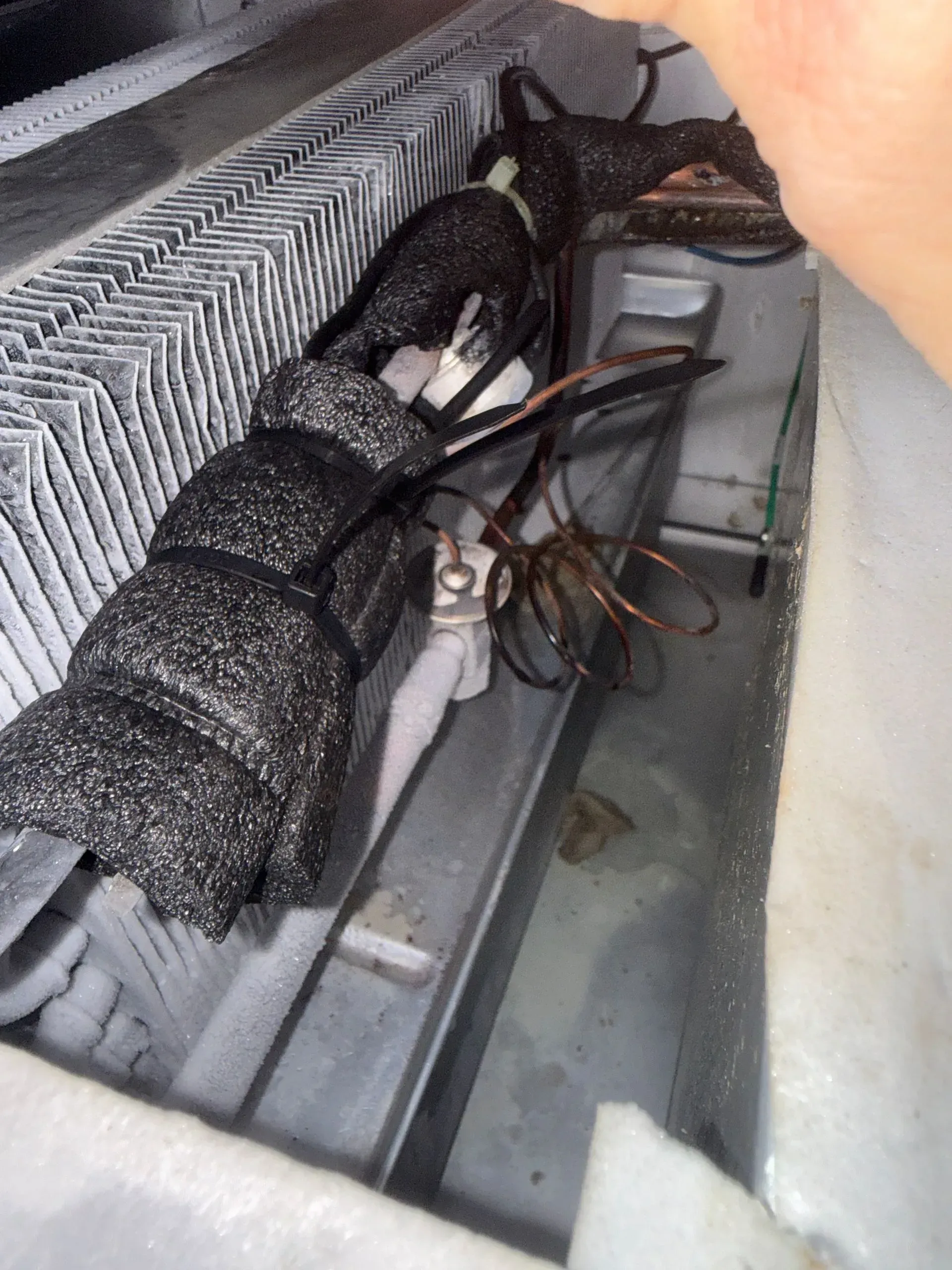 Bundle of insulated wires and wrapped cables in a narrow HVAC or utility space