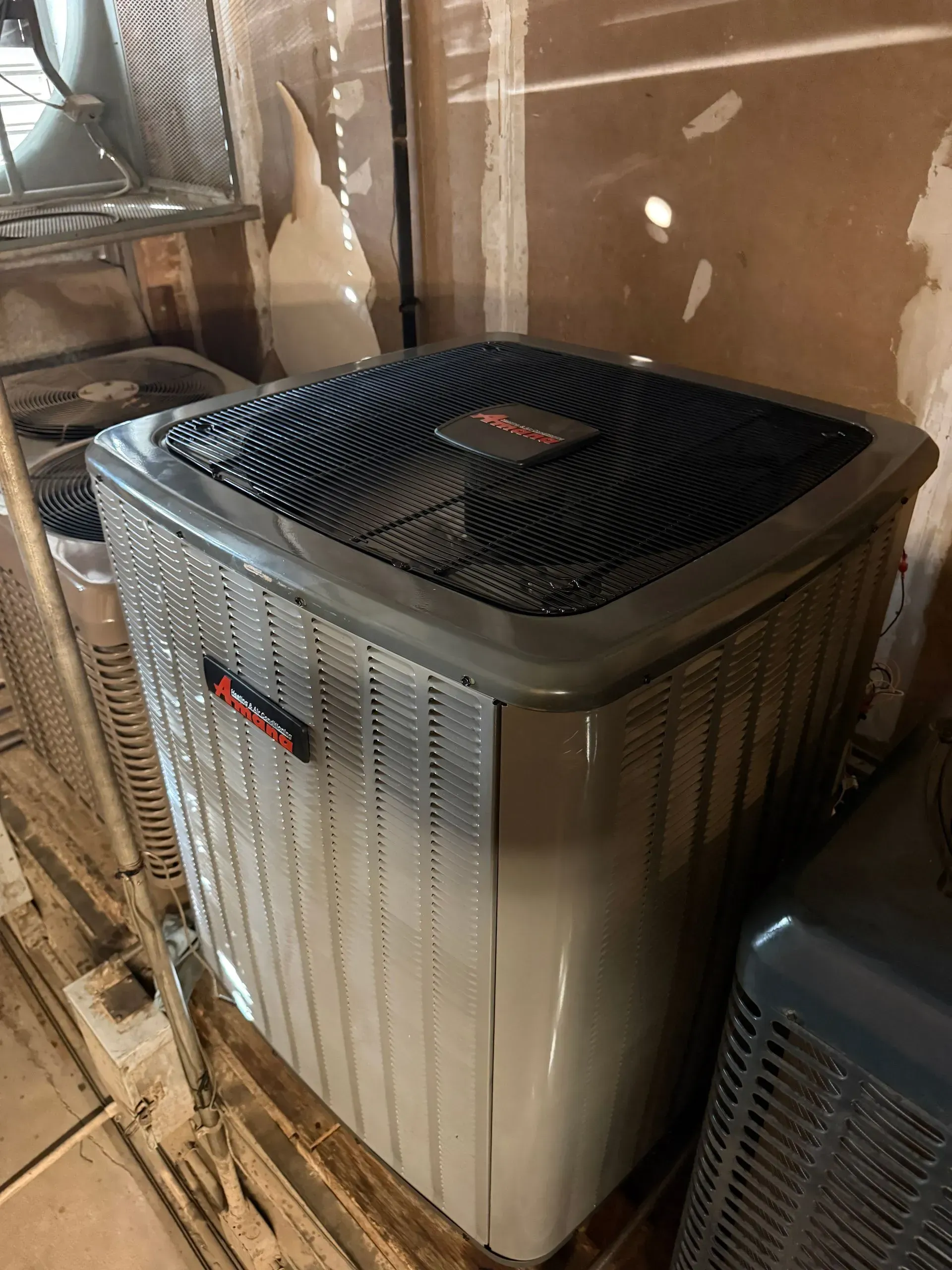 Large outdoor air conditioner unit with a black top in a narrow utility area
