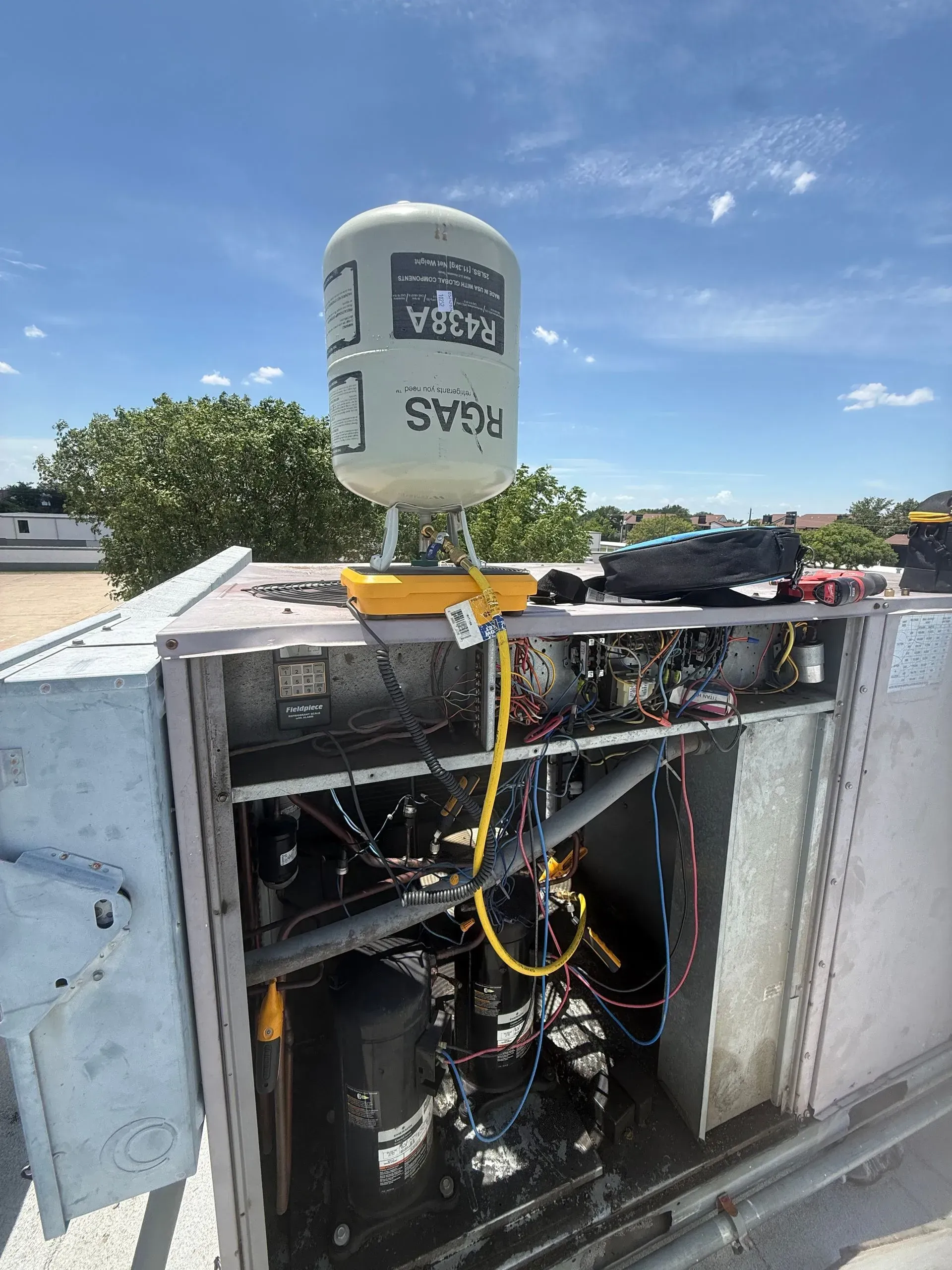 Open electrical cabinet with wiring and rooftop sensor beneath a blue sky