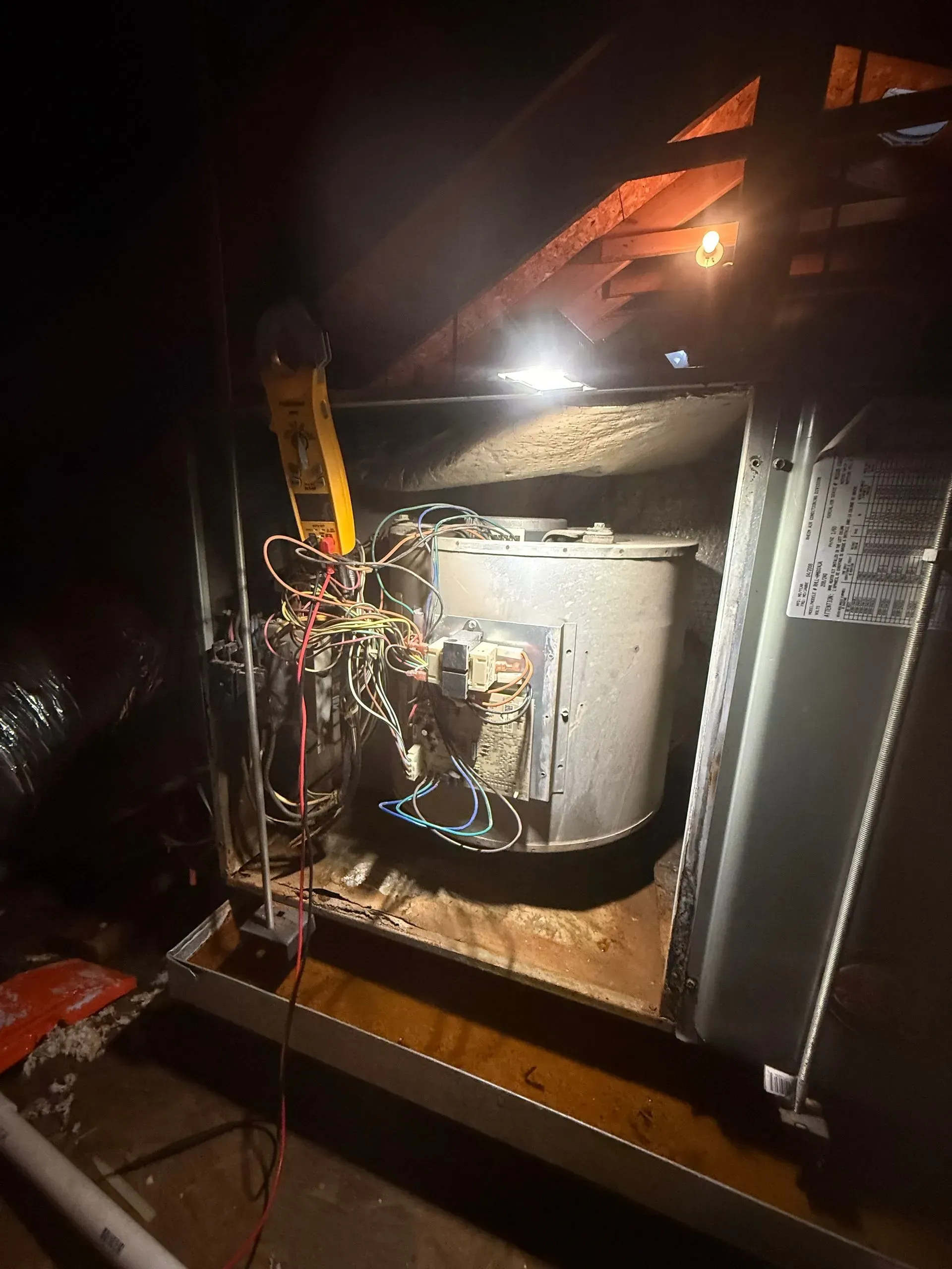 Damaged metal equipment inside a dark, wet industrial compartment, lit by a bright work light