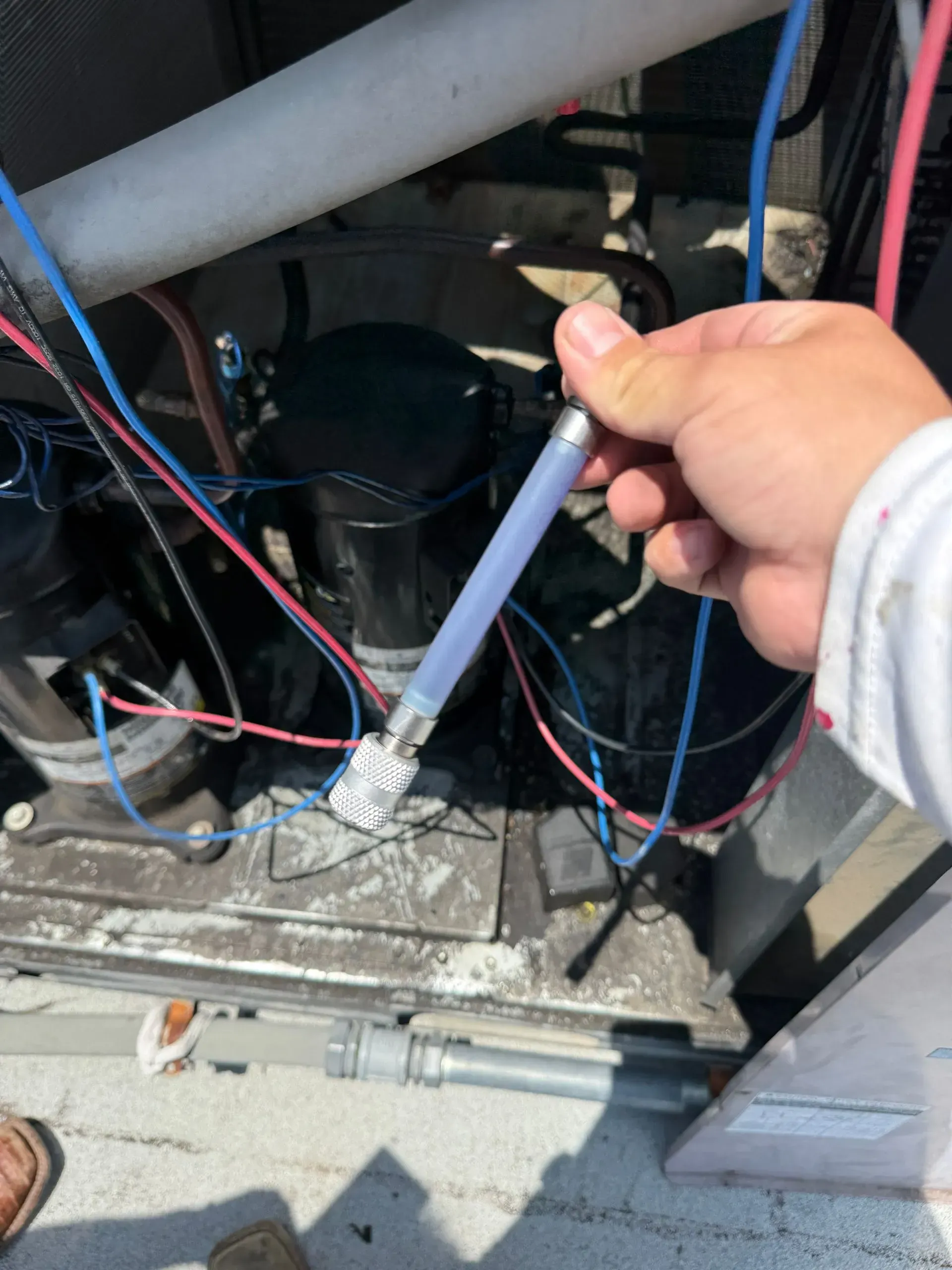 Hand holding a lit torch inside an electrical panel with exposed wires and components