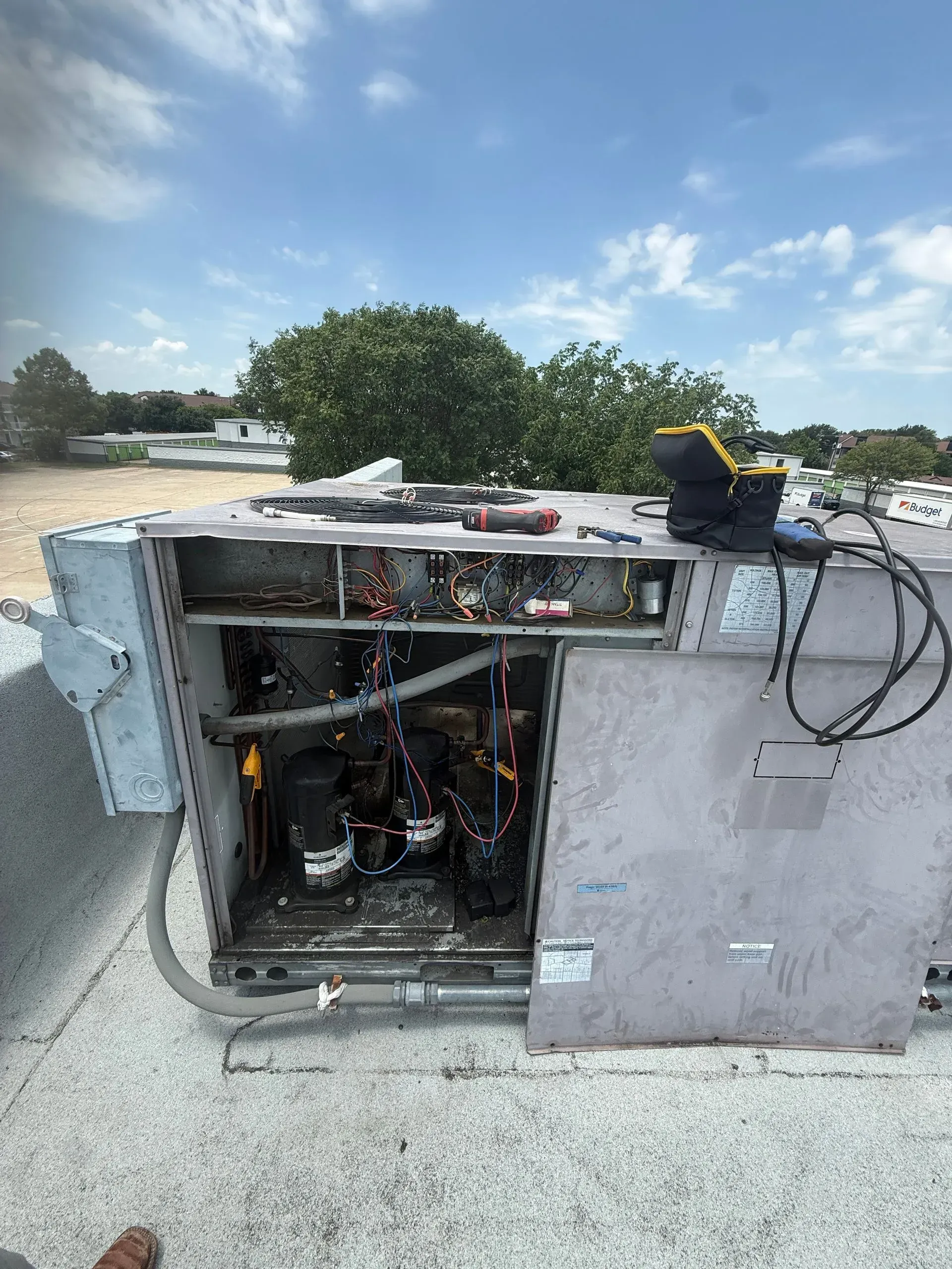Overturned metal equipment cabinet with exposed wiring on a roadside under a blue sky