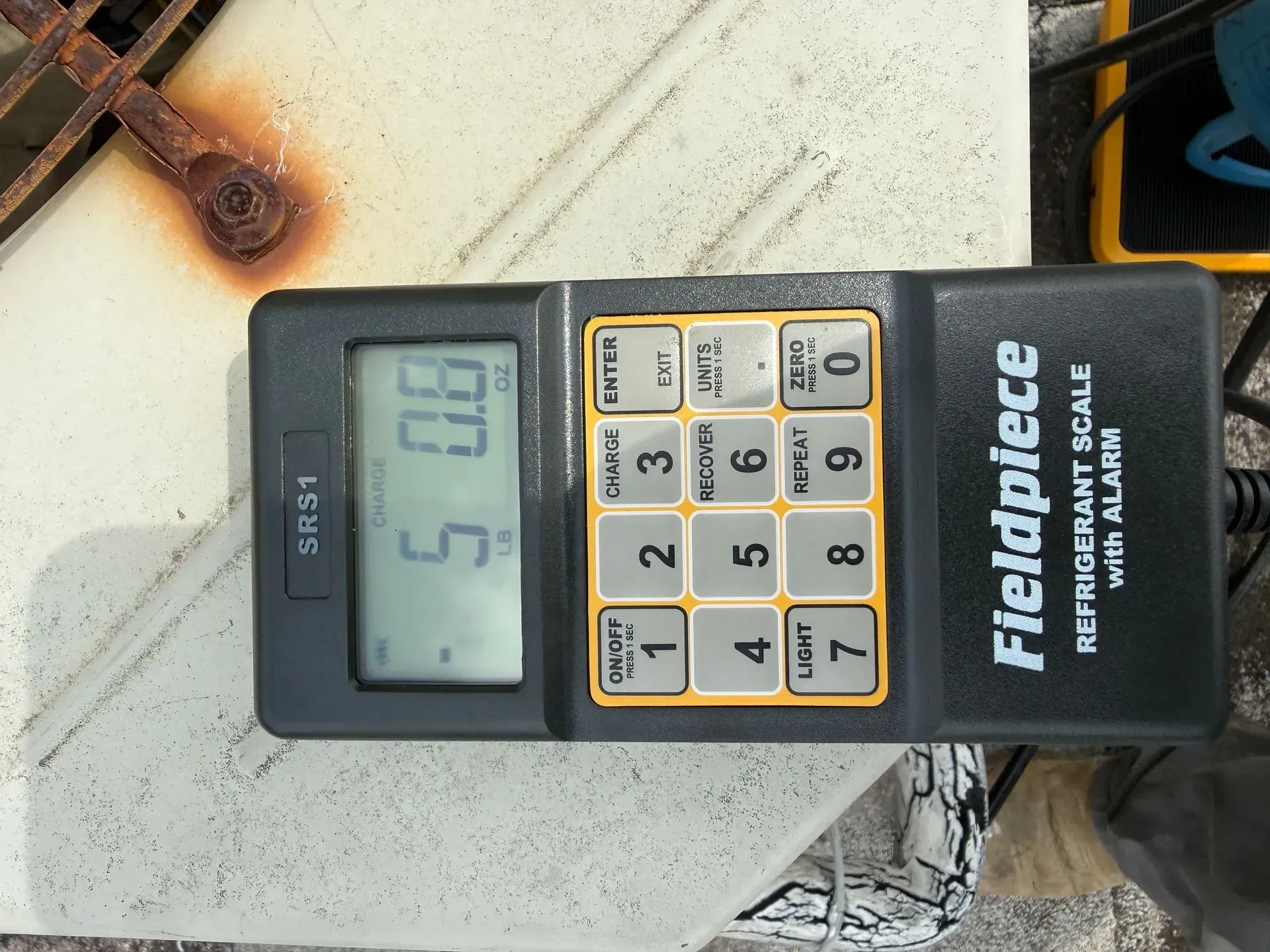 Fieldpiece multimeter on a white rooftop surface, displaying 51.0 on the screen.