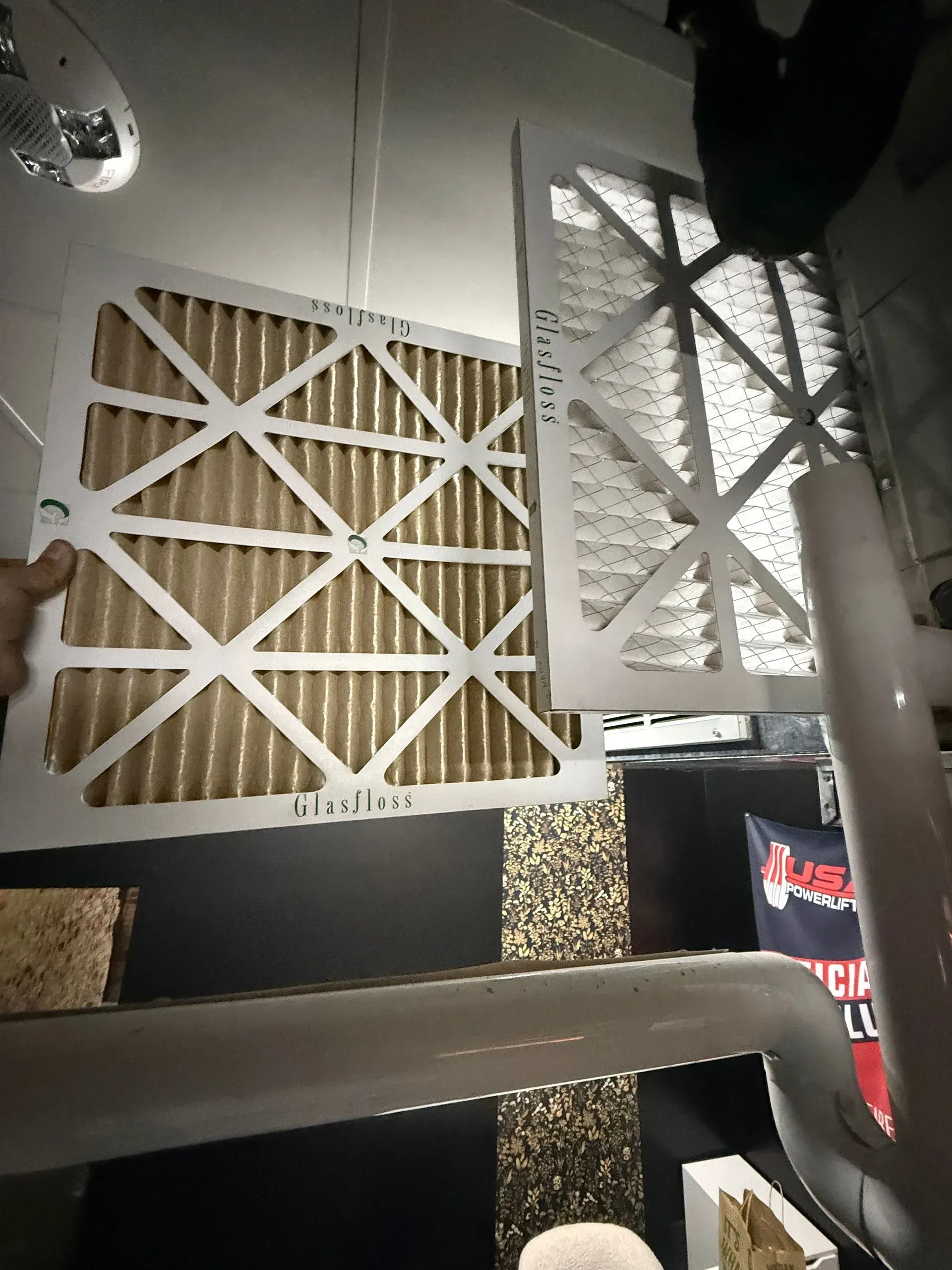 Two white crisscross-pattern wall panels above a dark shelf in a modern interior