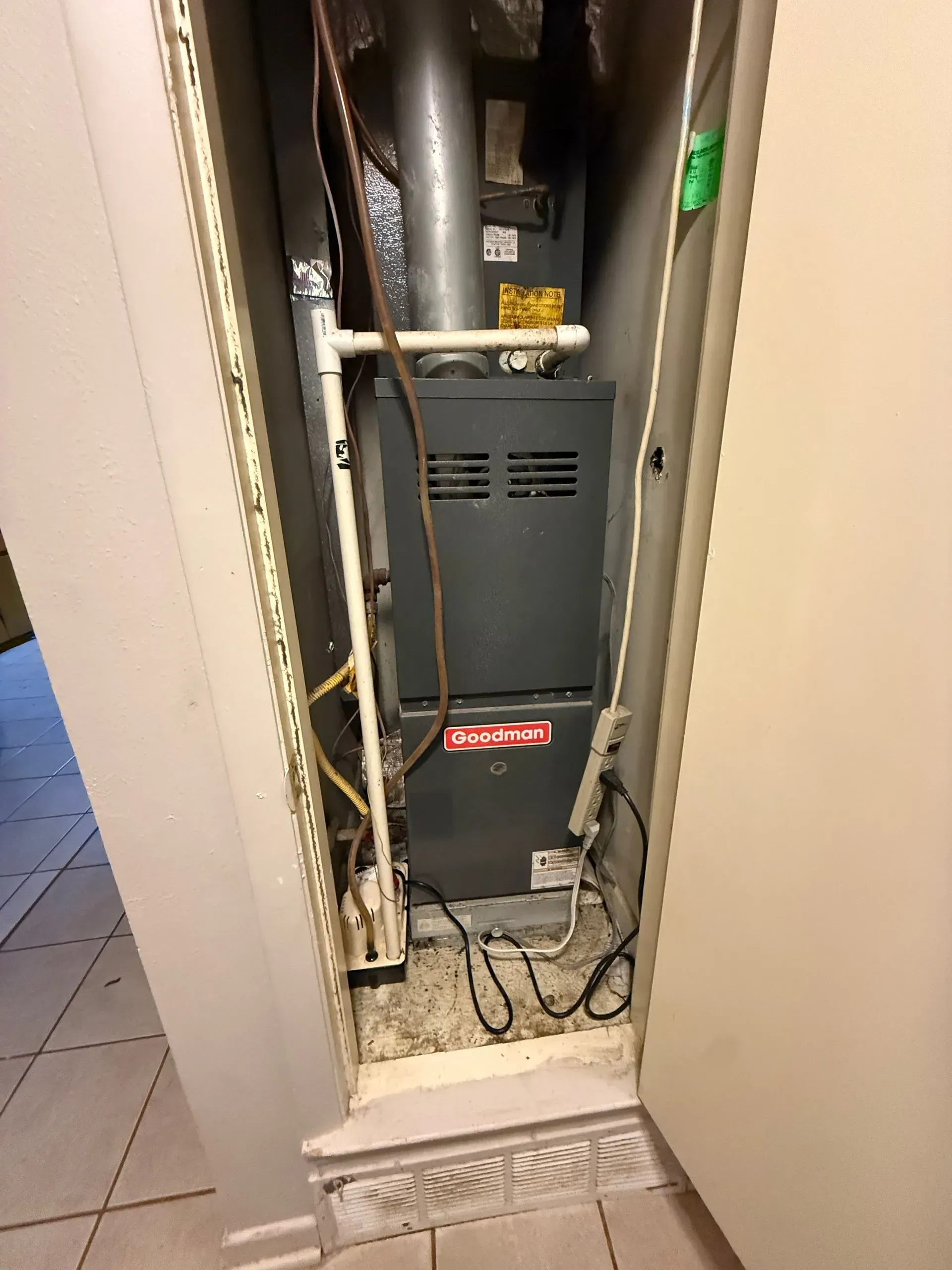 Open utility closet with exposed wiring, a gray furnace, and a tiled floor.
