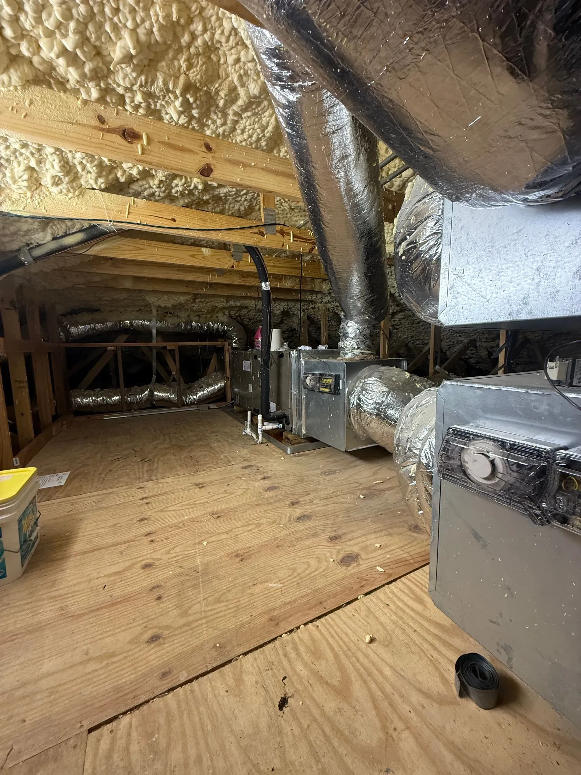 Crawlspace with exposed insulation, ductwork, and wooden joists under a home