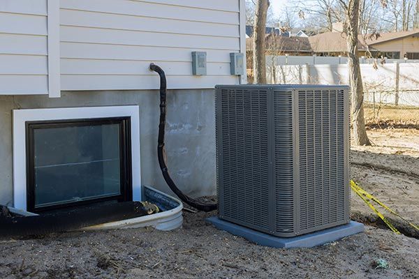 House exterior with a basement window, HVAC unit, and utility lines along the foundation
